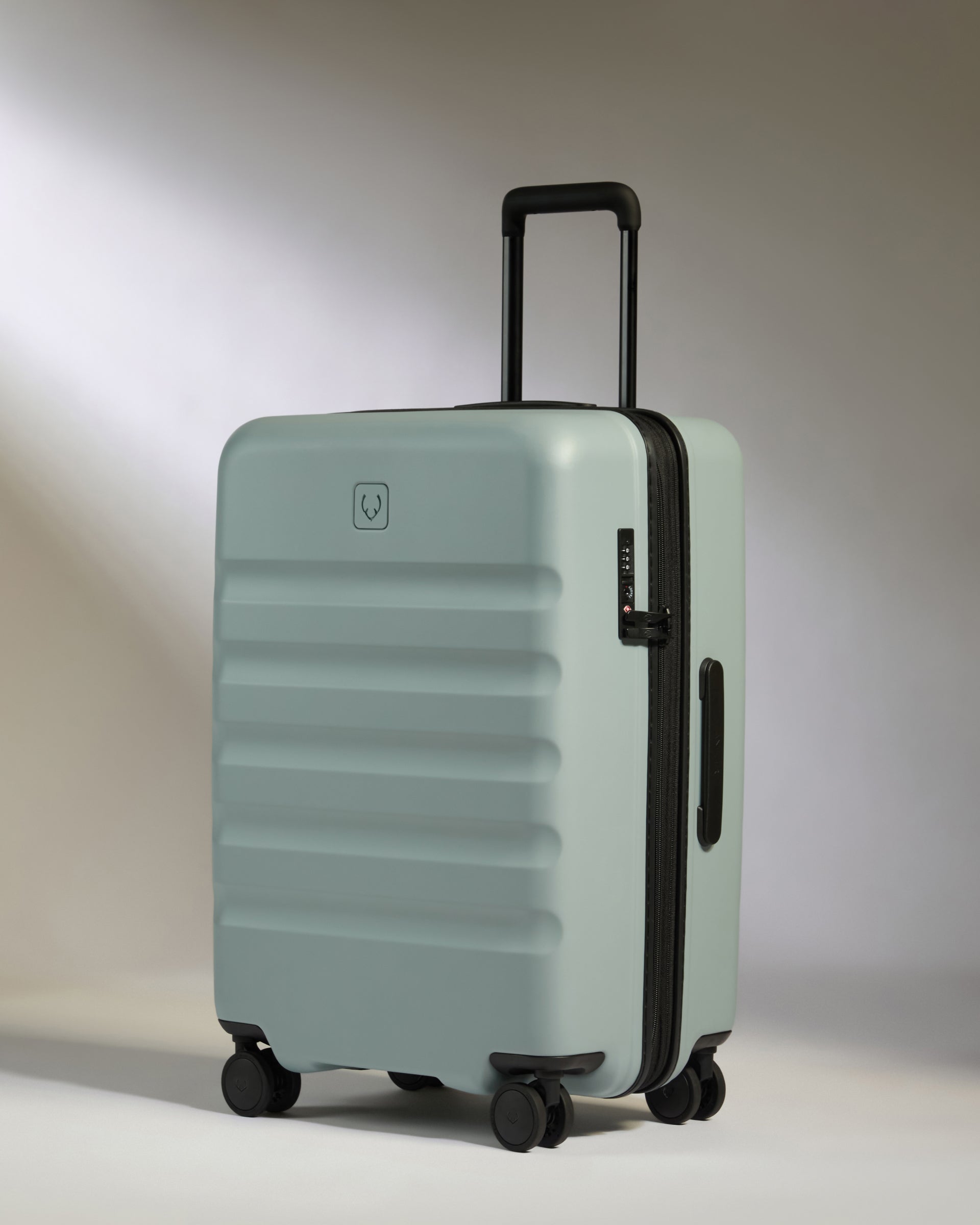 Light blue suitcase with black handle and wheels on a neutral background