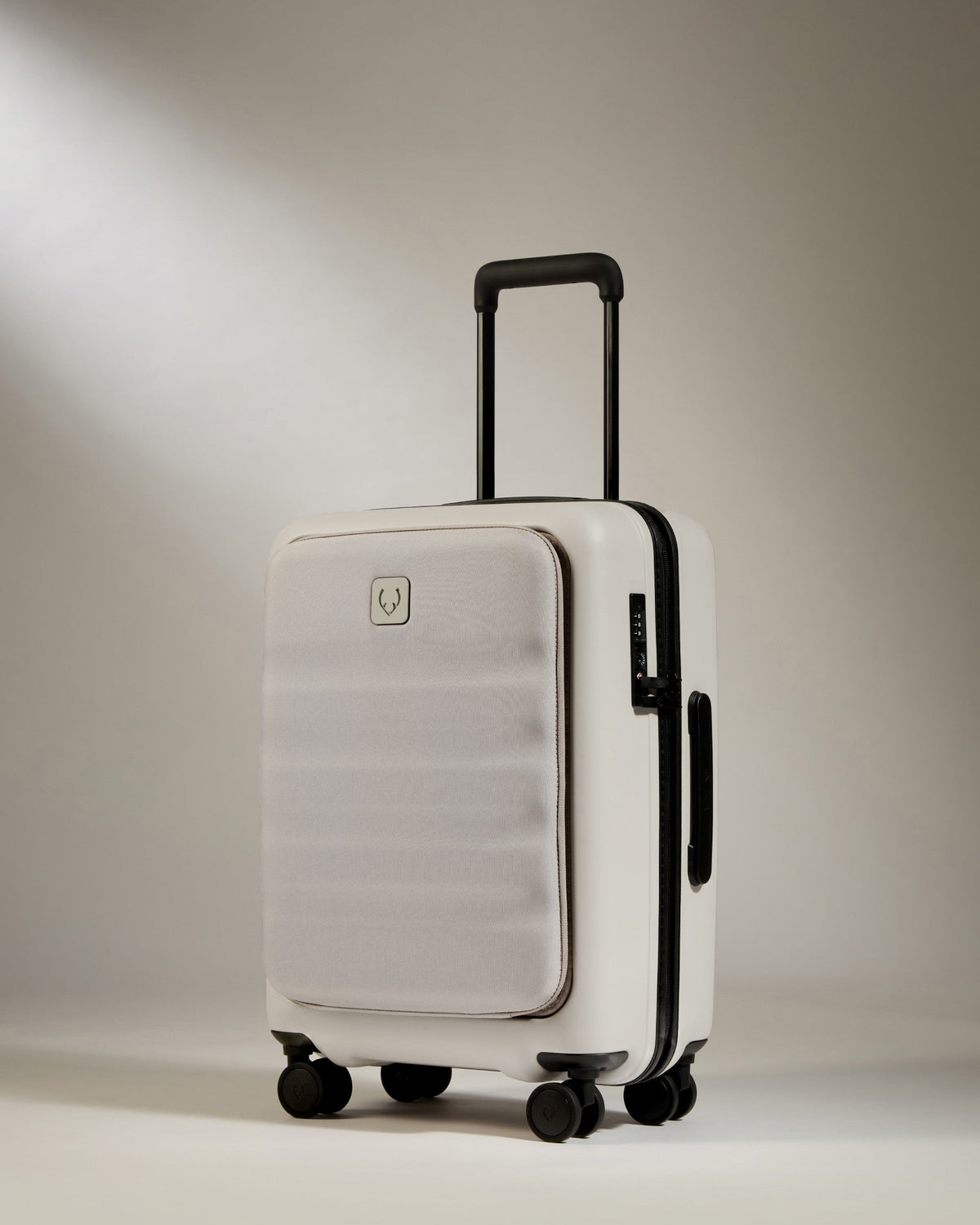 Beige suitcase with black handle and wheels on a light gray background