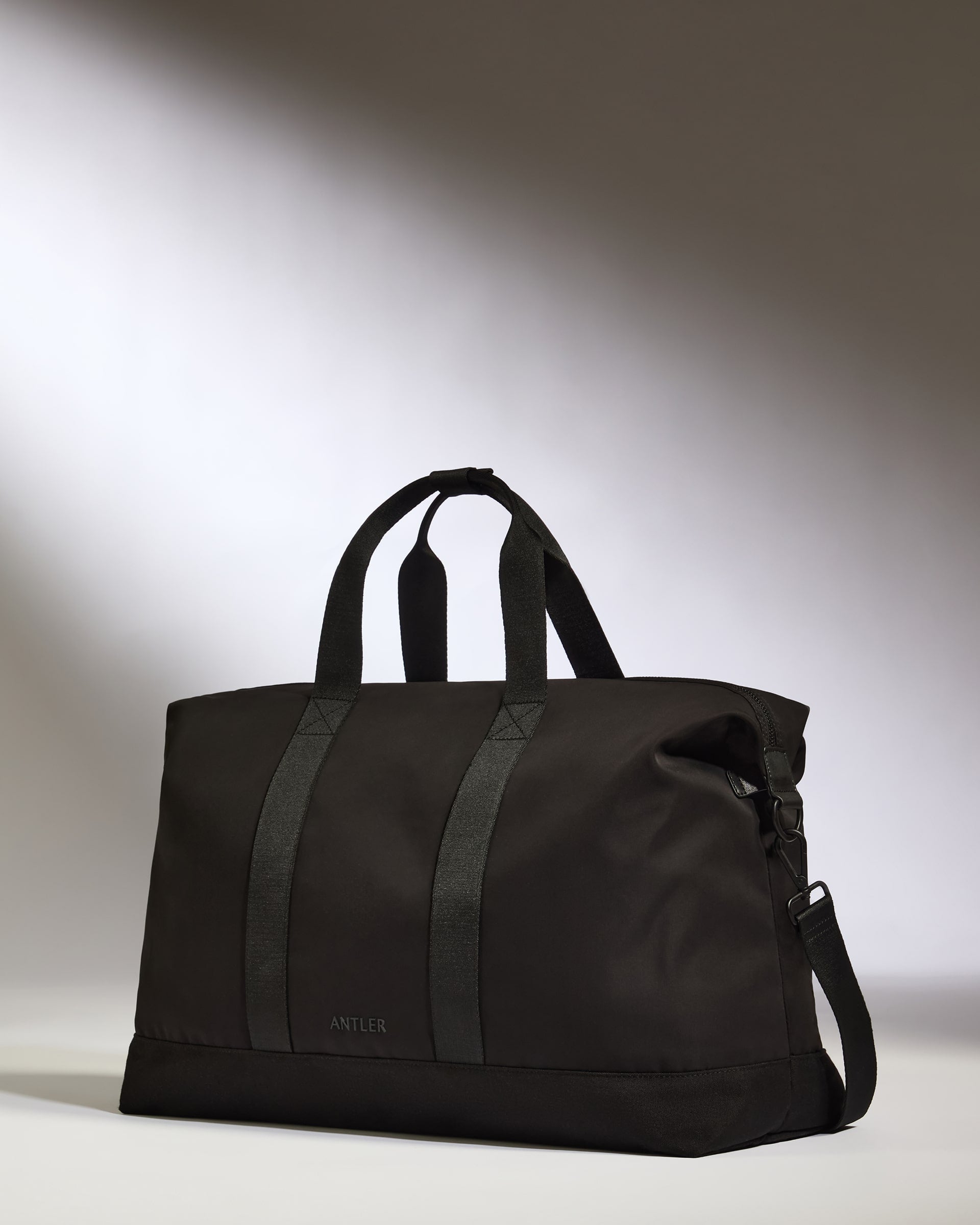 Black duffel bag with visible brand name on a gray background