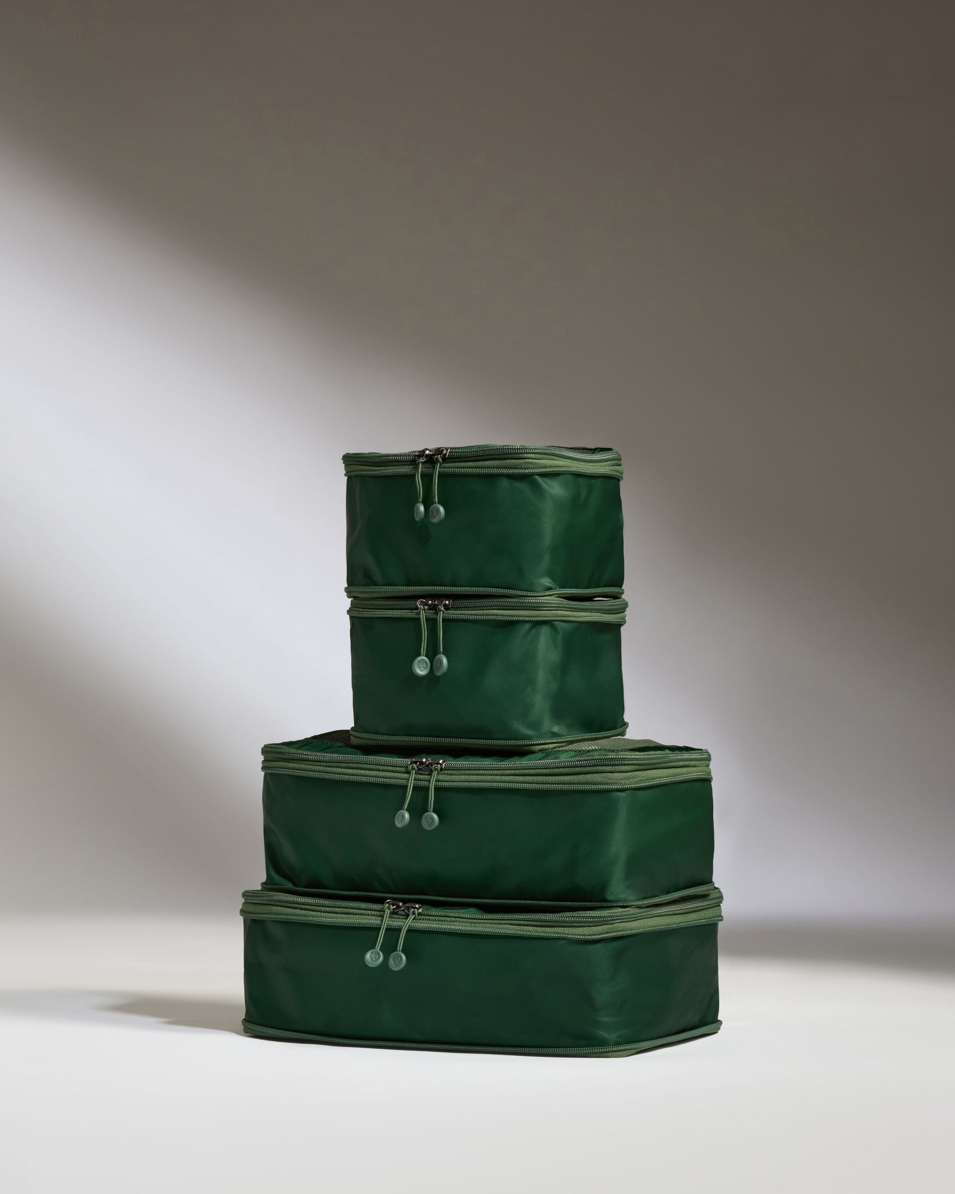 Three green storage boxes stacked on a light background
