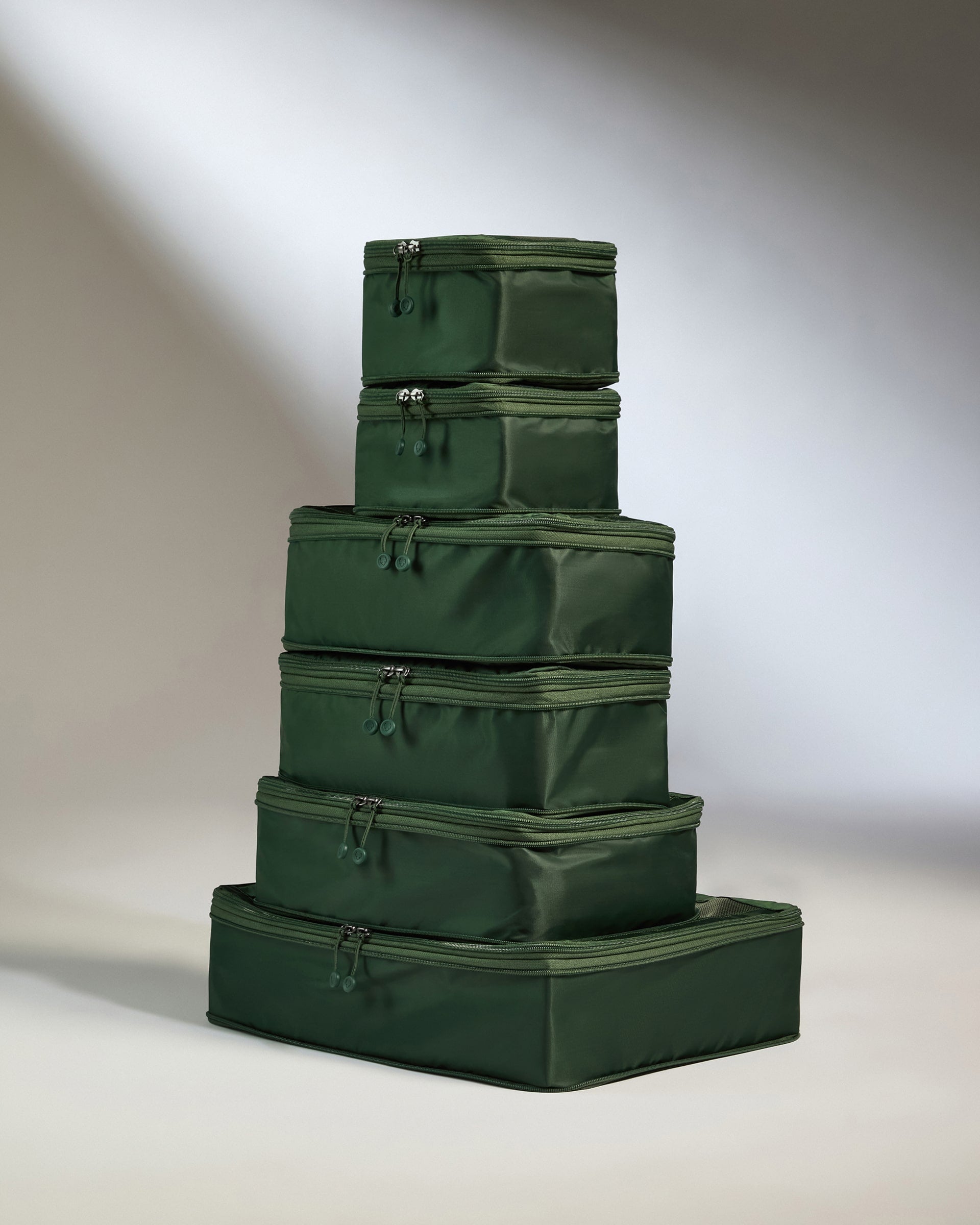 Stack of green packing cubes on a neutral background