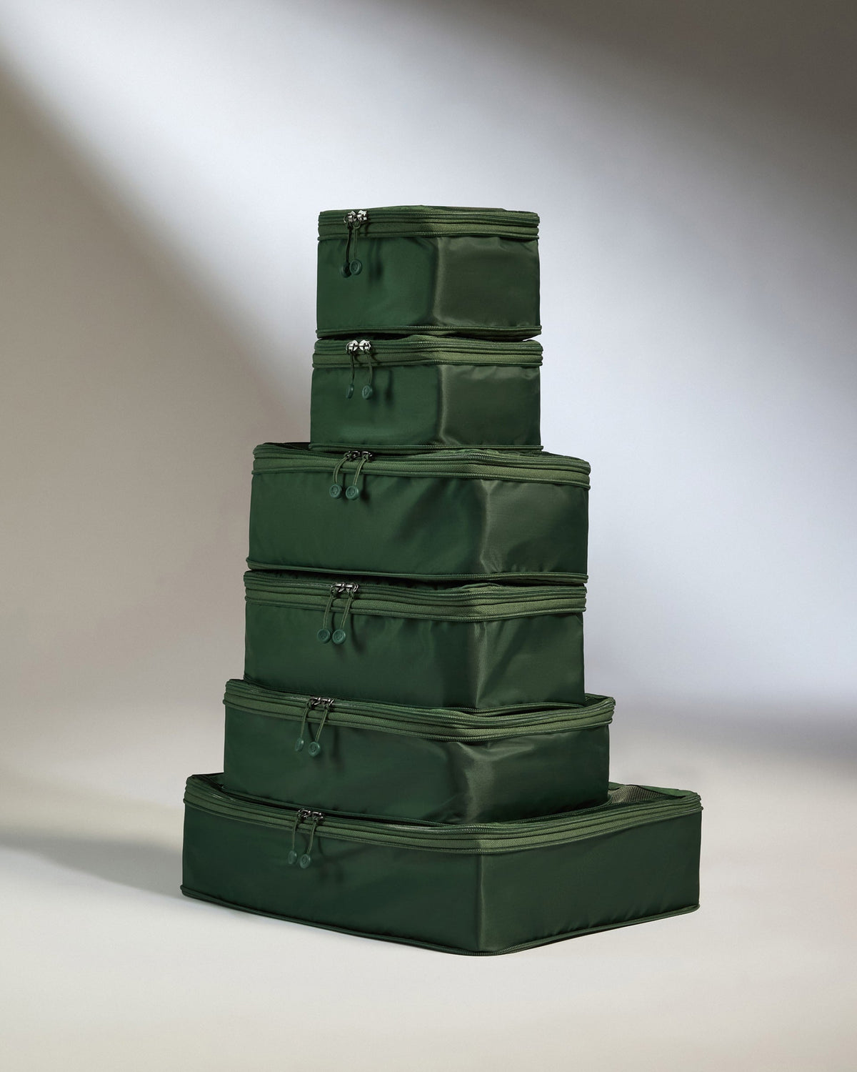 Stack of green packing cubes on a neutral background