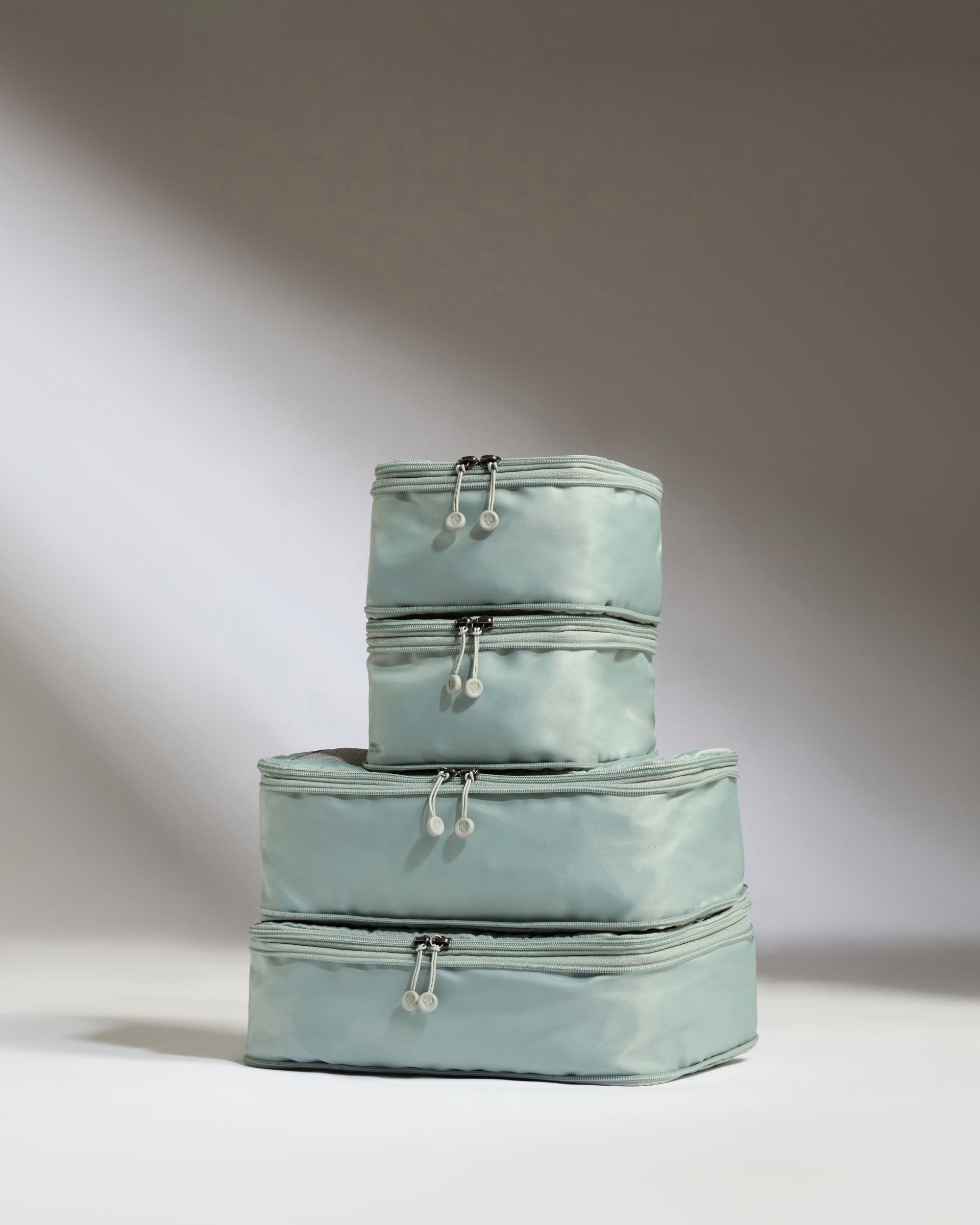 Set of three light blue packing cubes stacked on a white background