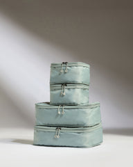 Set of three light blue packing cubes stacked on a white background