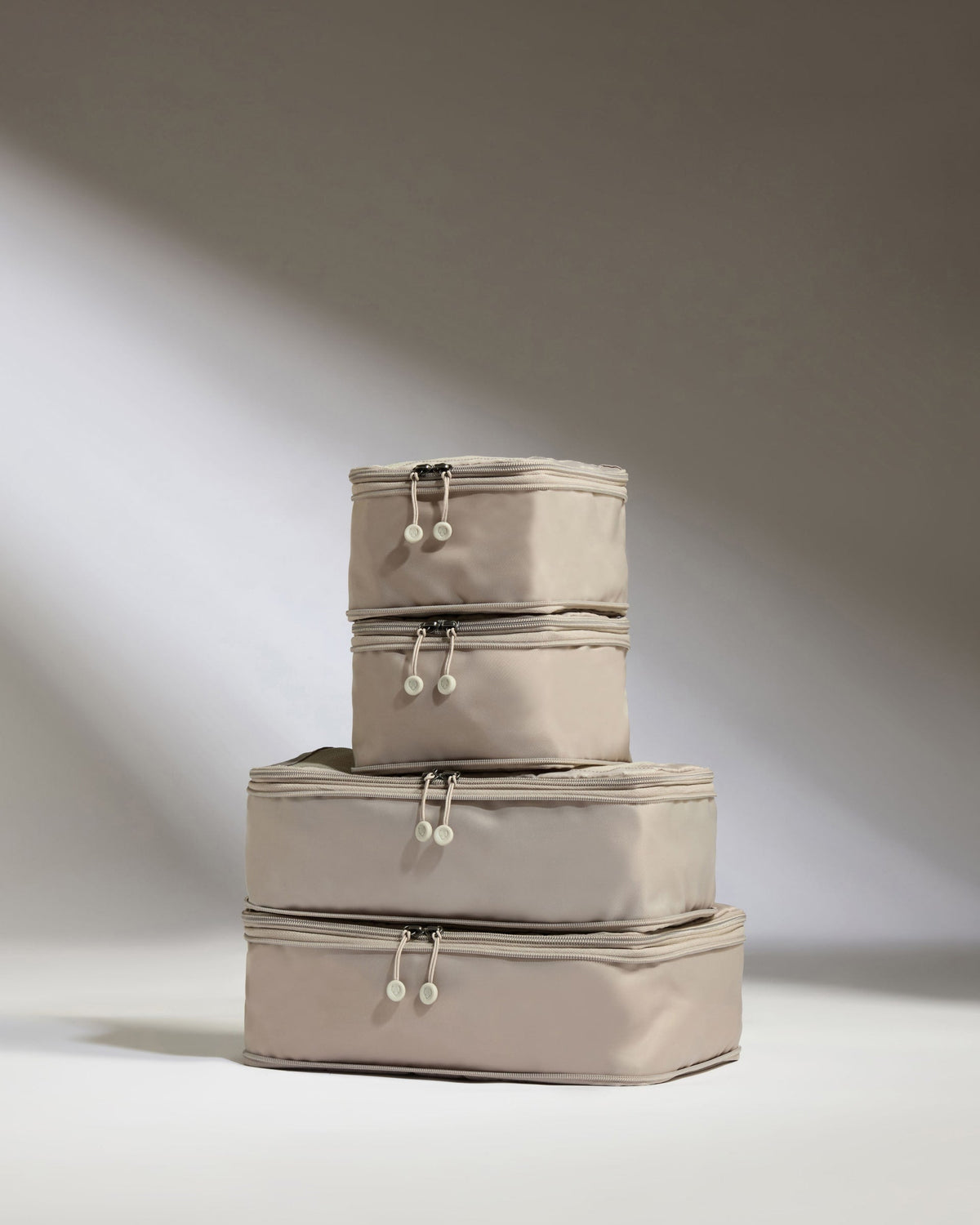 Set of three beige storage boxes stacked on a light background