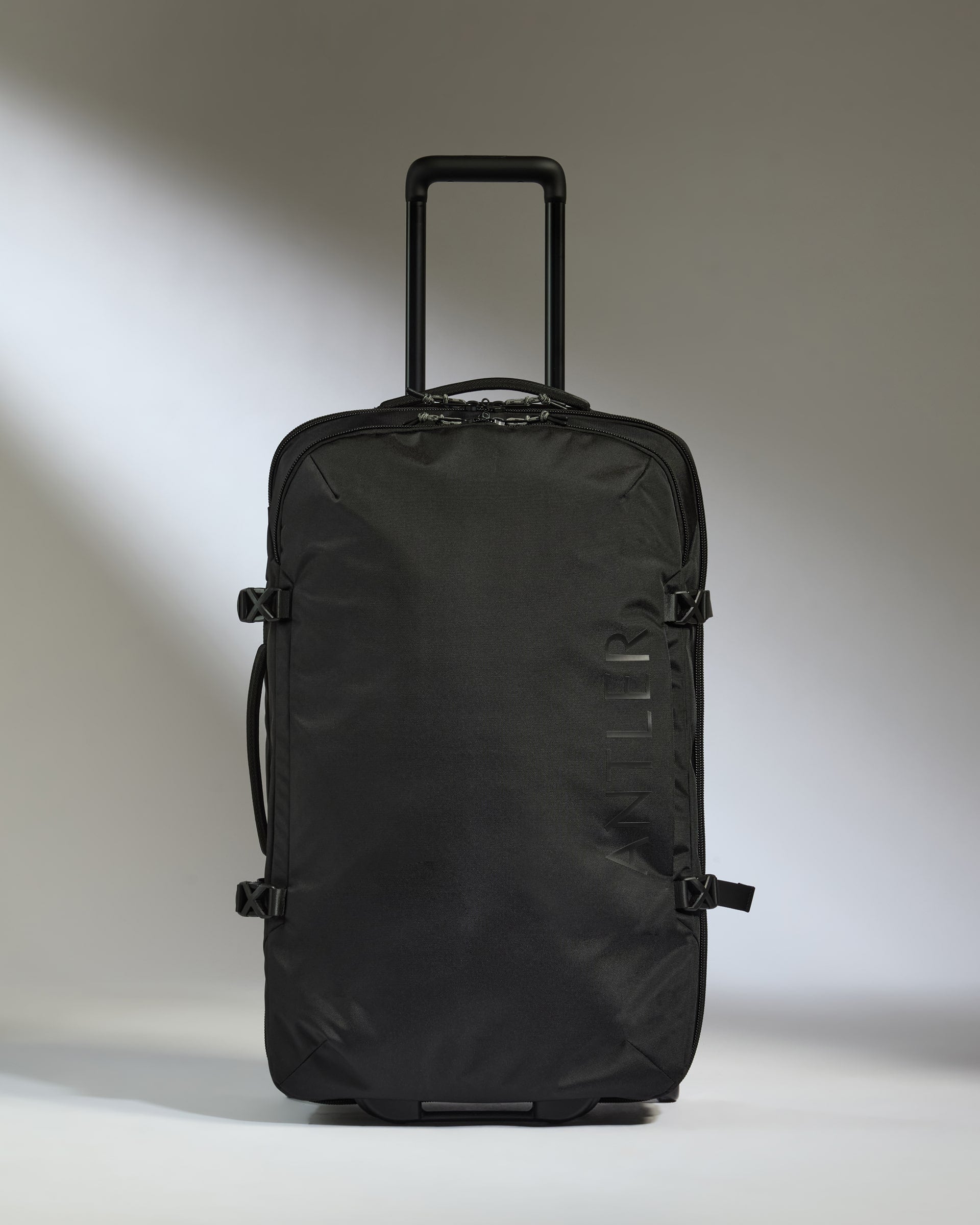 Black rolling suitcase on a light gray background