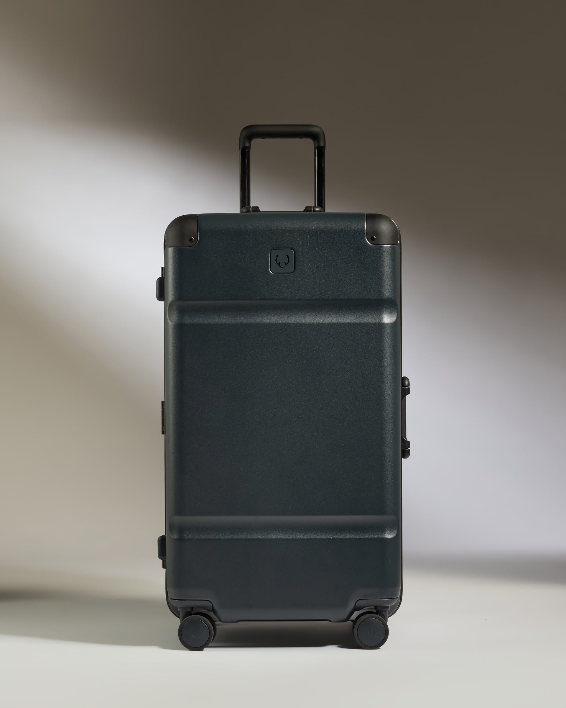 Black suitcase with a visible brand logo on a neutral background