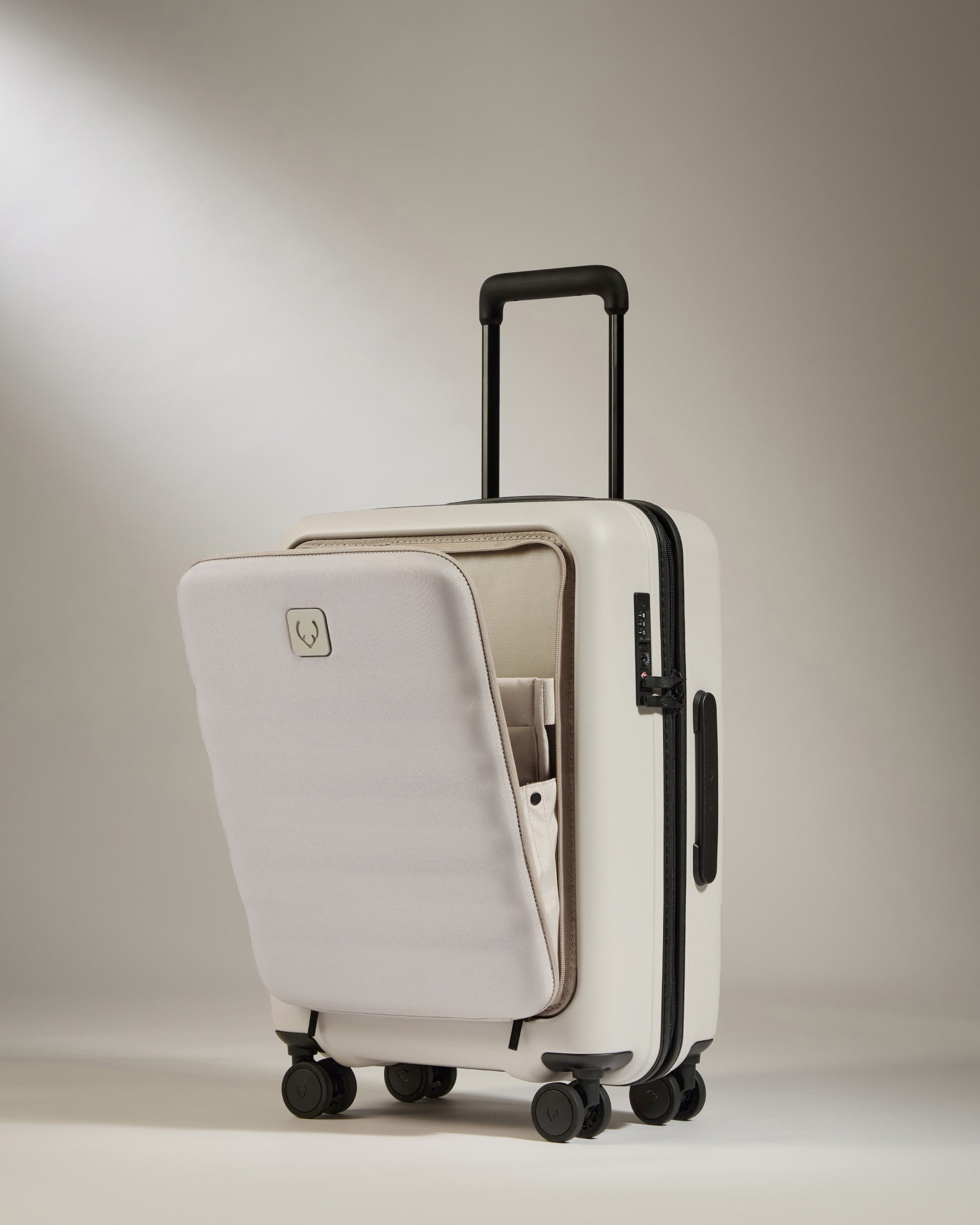 White suitcase with a black handle and wheels on a beige background