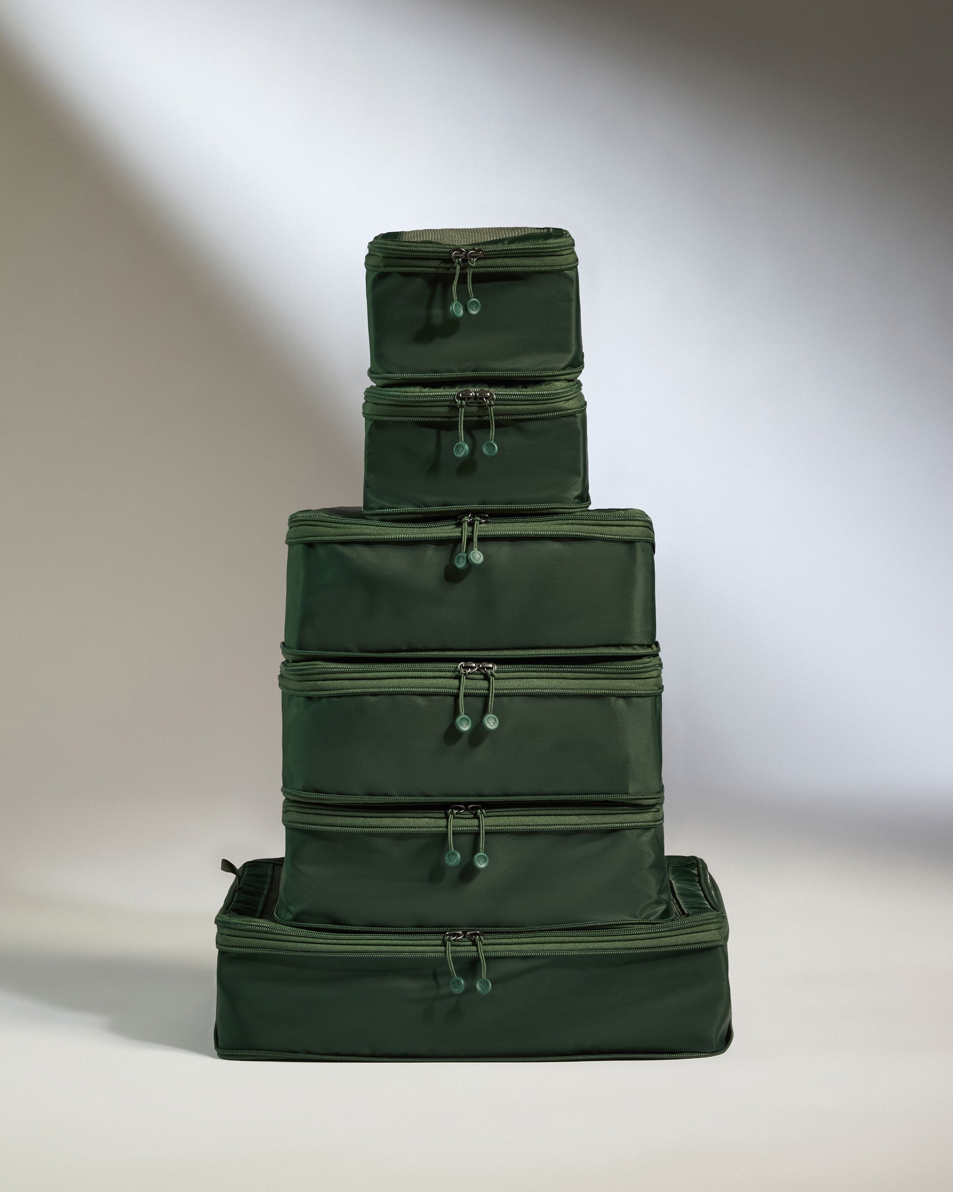 Stack of green packing cubes on a neutral background