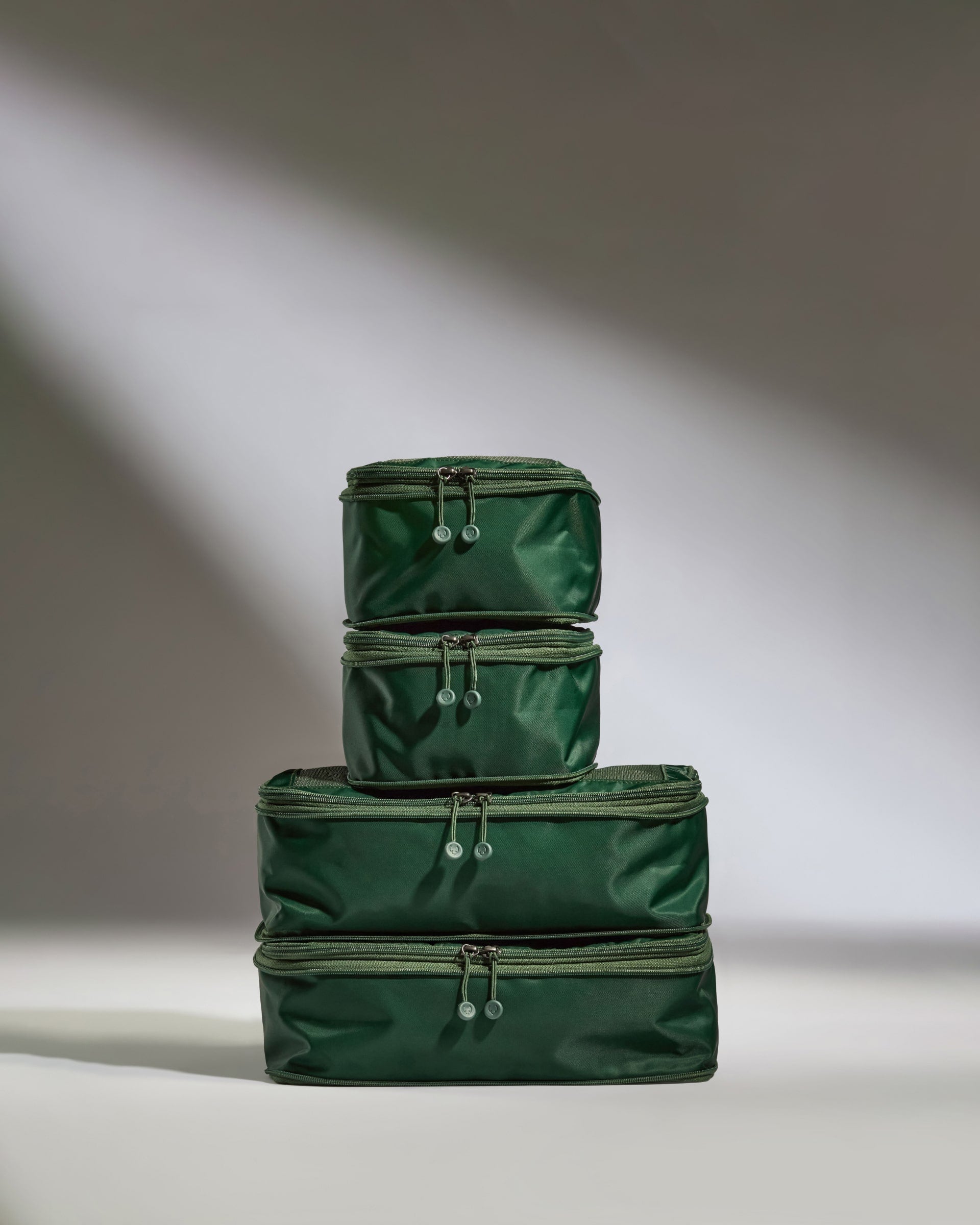 Stack of green packing cubes on a neutral background