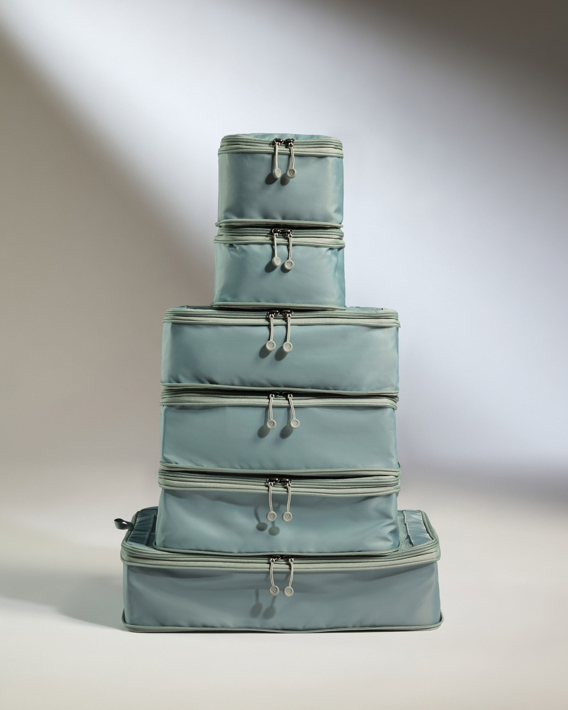 Stack of light blue suitcases on a neutral background