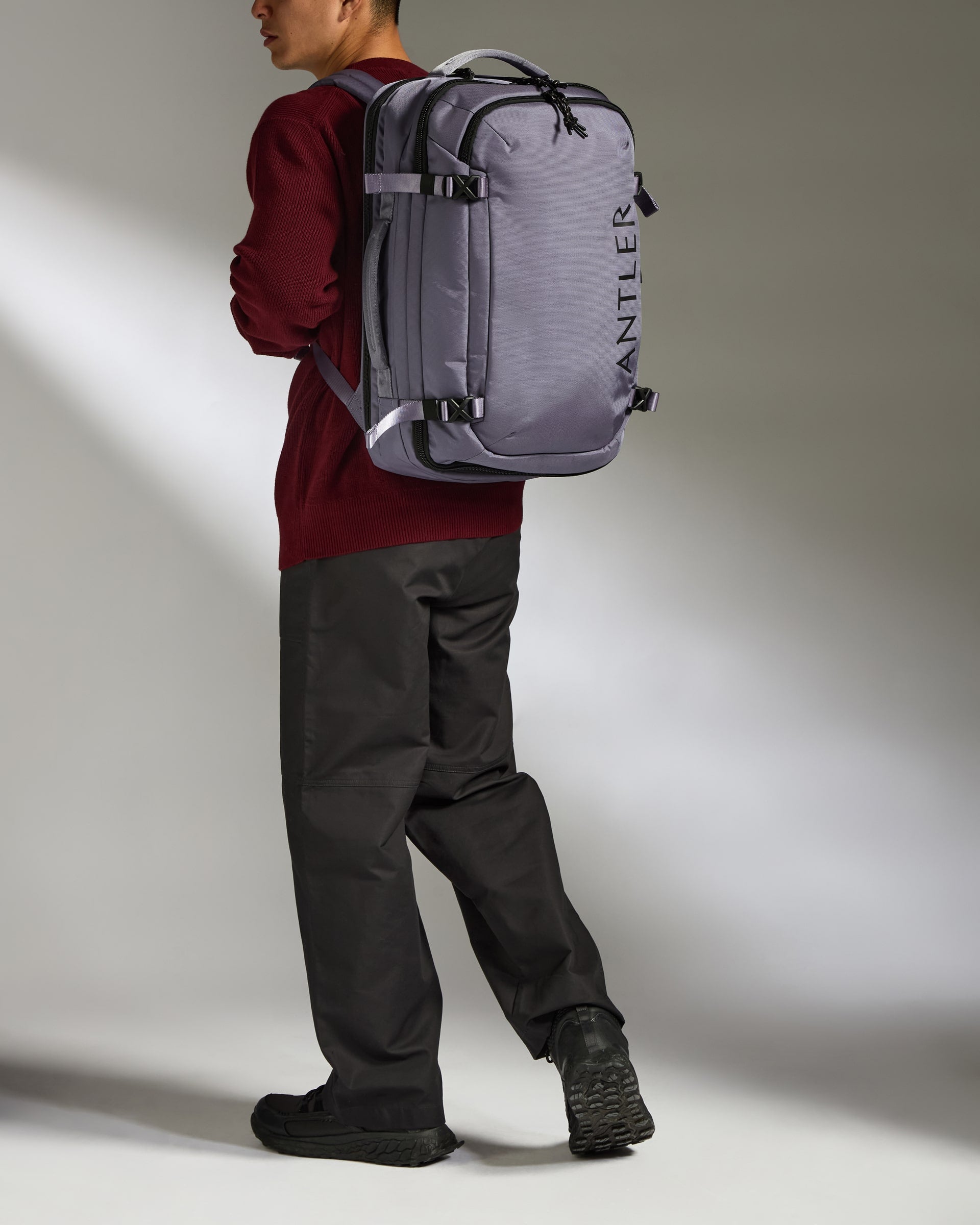 Person wearing a gray Antler backpack against a neutral background