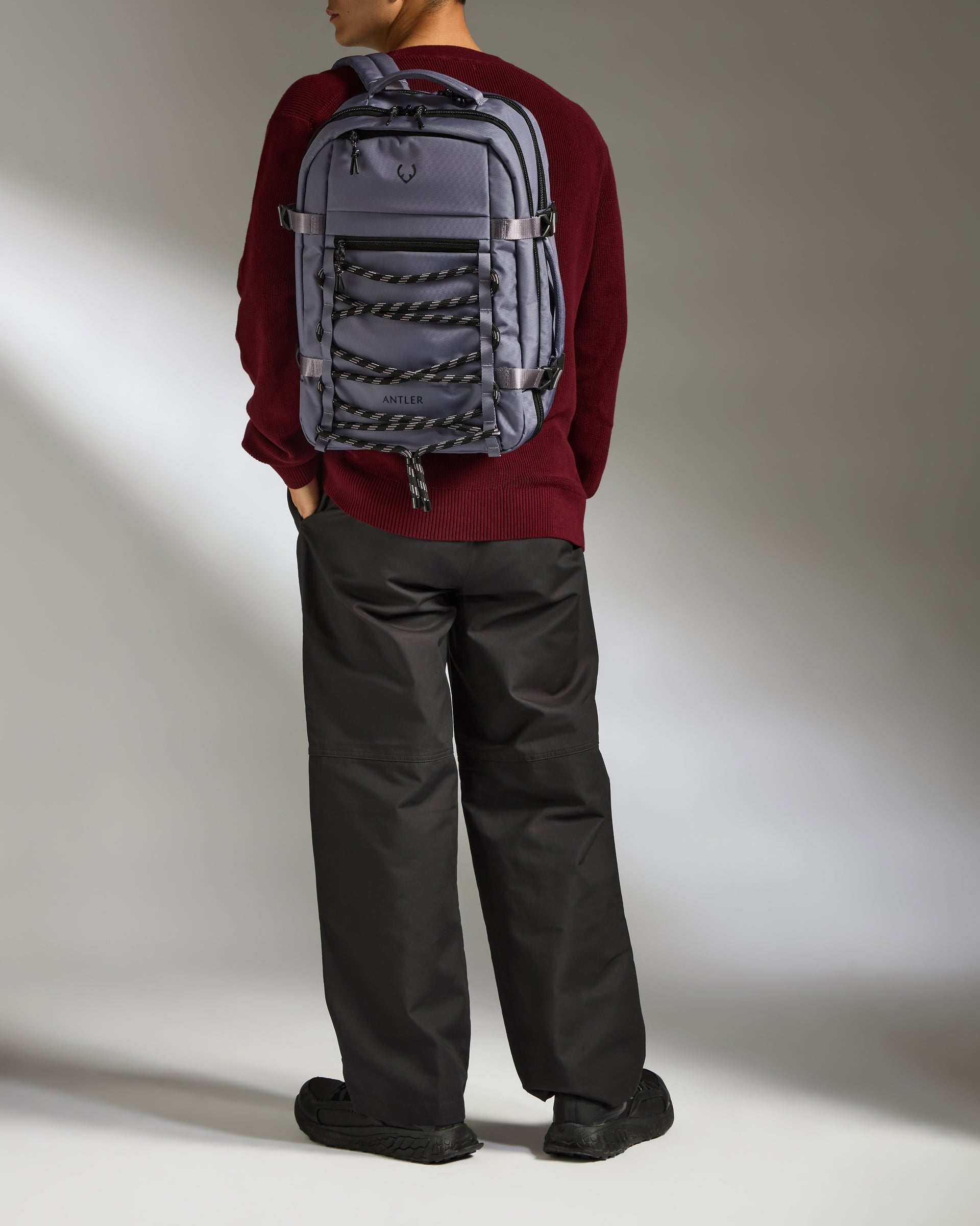 Person wearing a gray backpack against a plain background