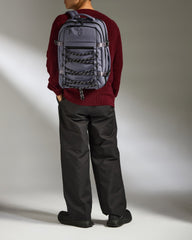 Person wearing a gray backpack against a plain background