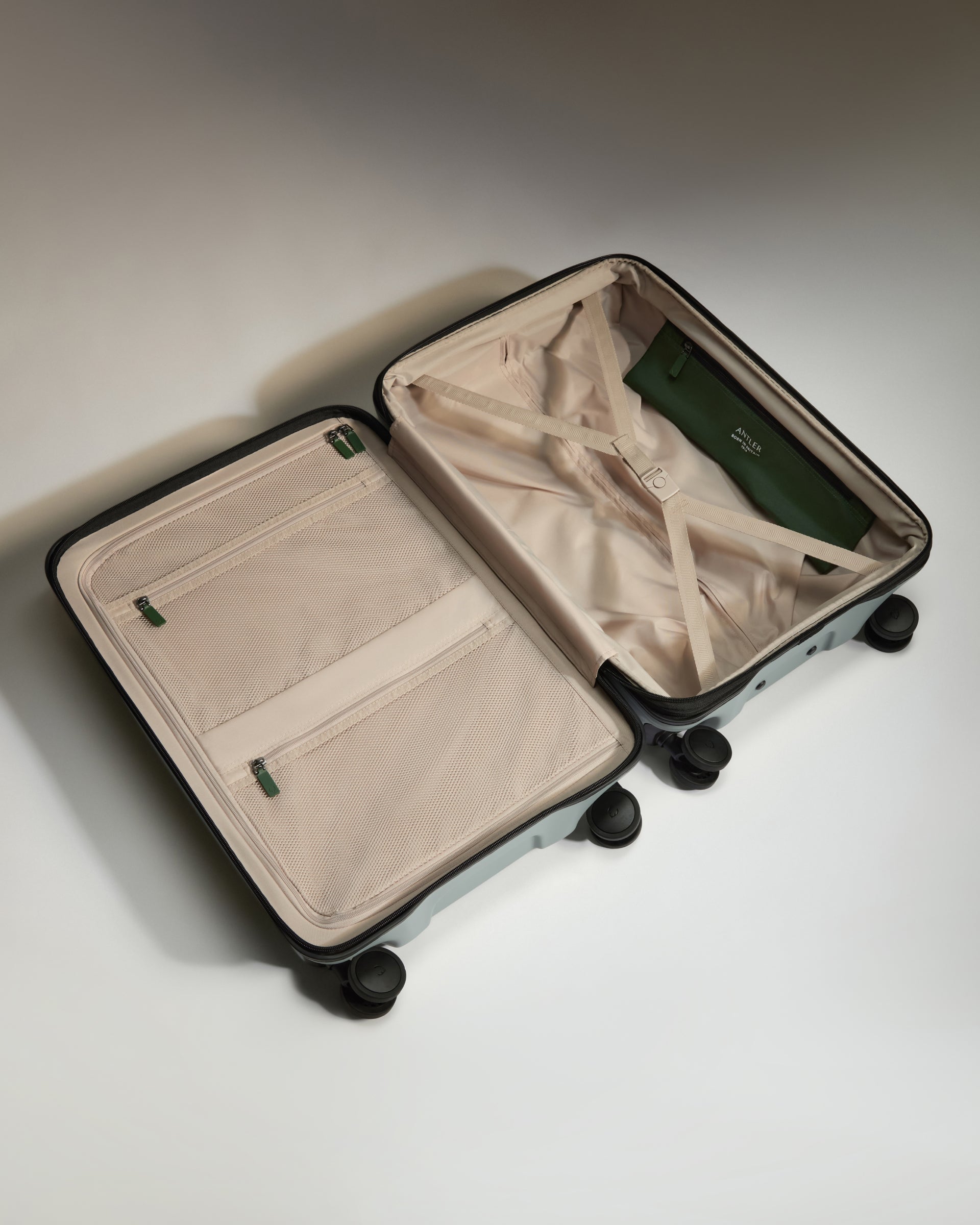 Open beige suitcase with green interior on a light gray background
