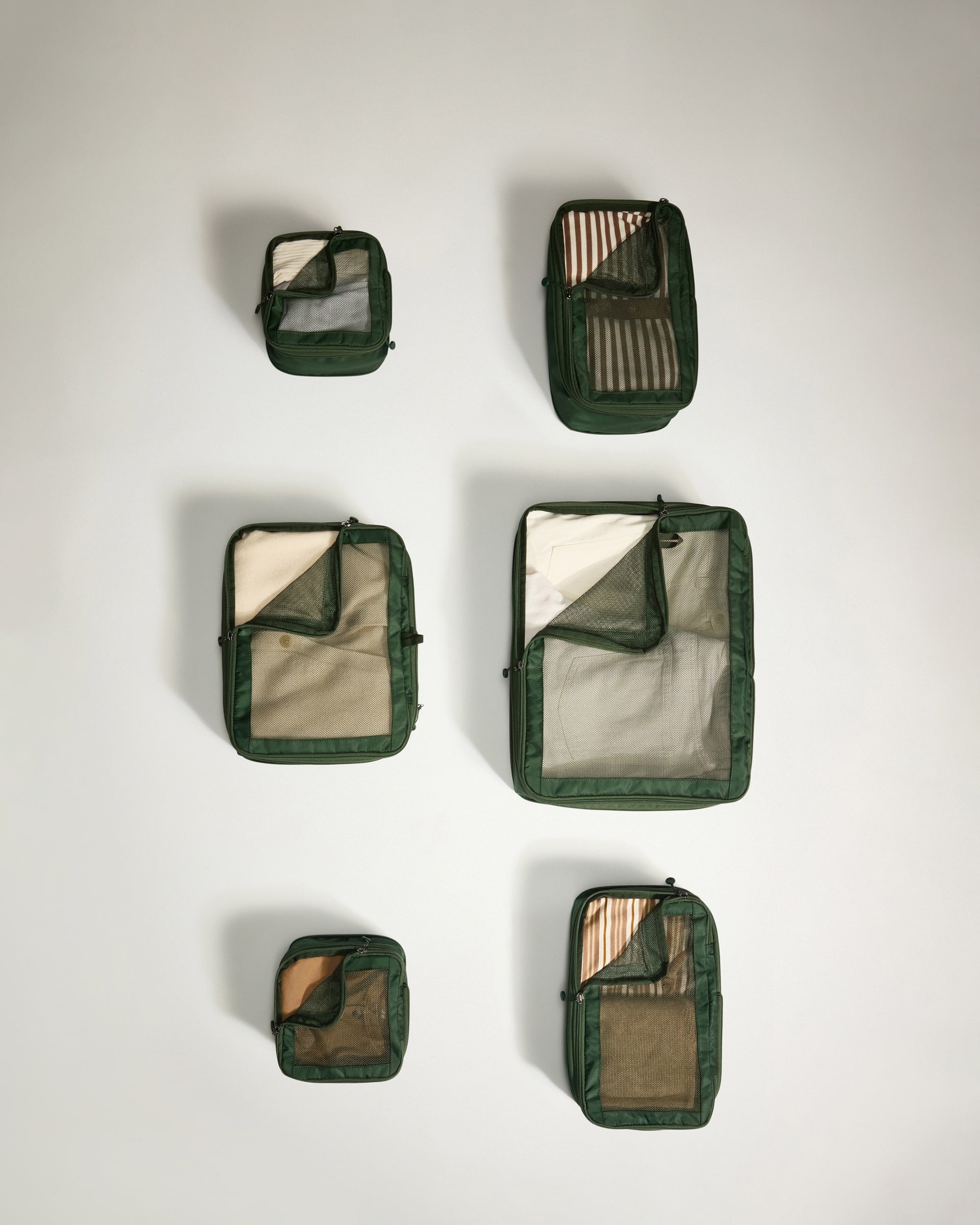Set of green travel packing cubes on a light gray background