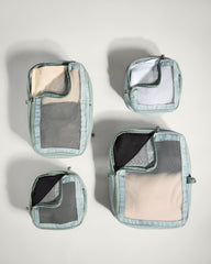 Set of four travel packing cubes with different compartments on a light gray background