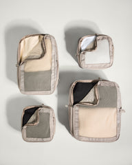 Set of four gray and beige travel packing cubes on a light gray background