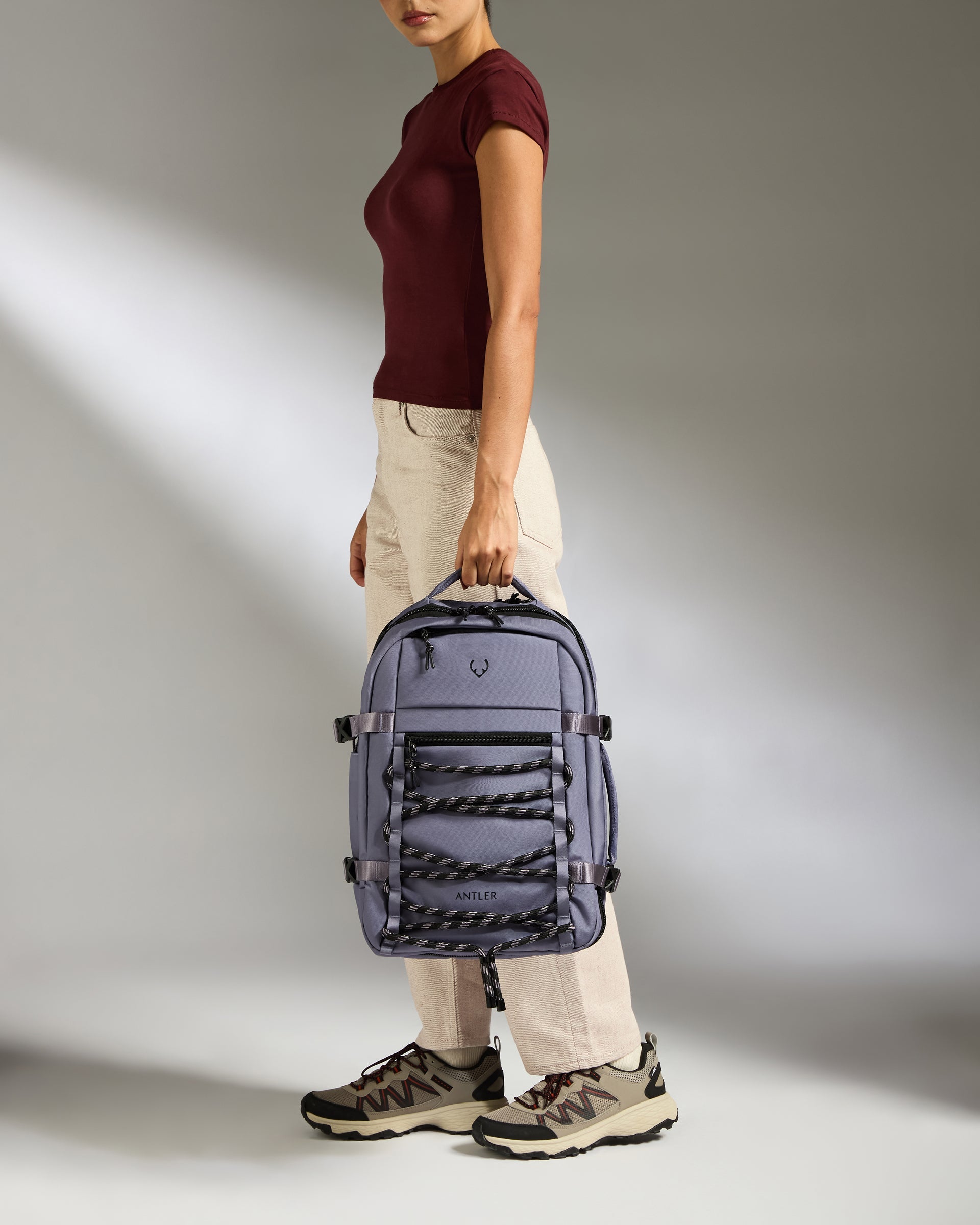 Person holding a purple backpack against a neutral background