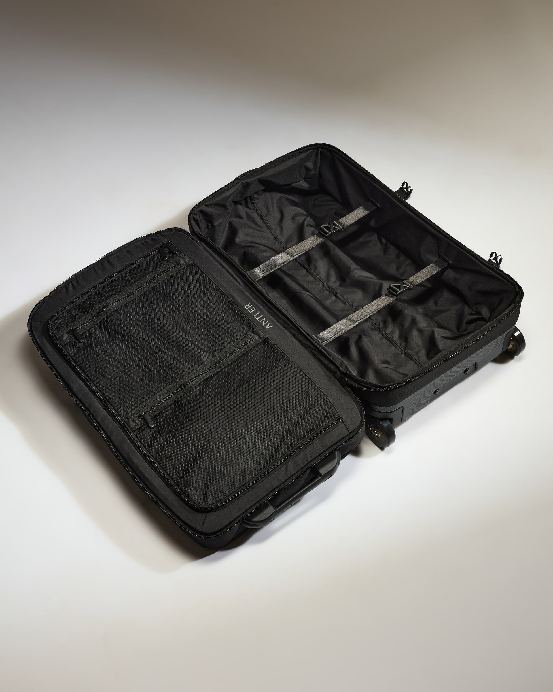 Black suitcase with open compartment on a light gray background