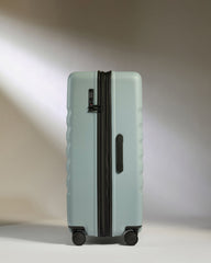 Light blue suitcase with black handle and wheels on a neutral background