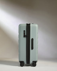 Light blue suitcase with black handle and wheels on a white background