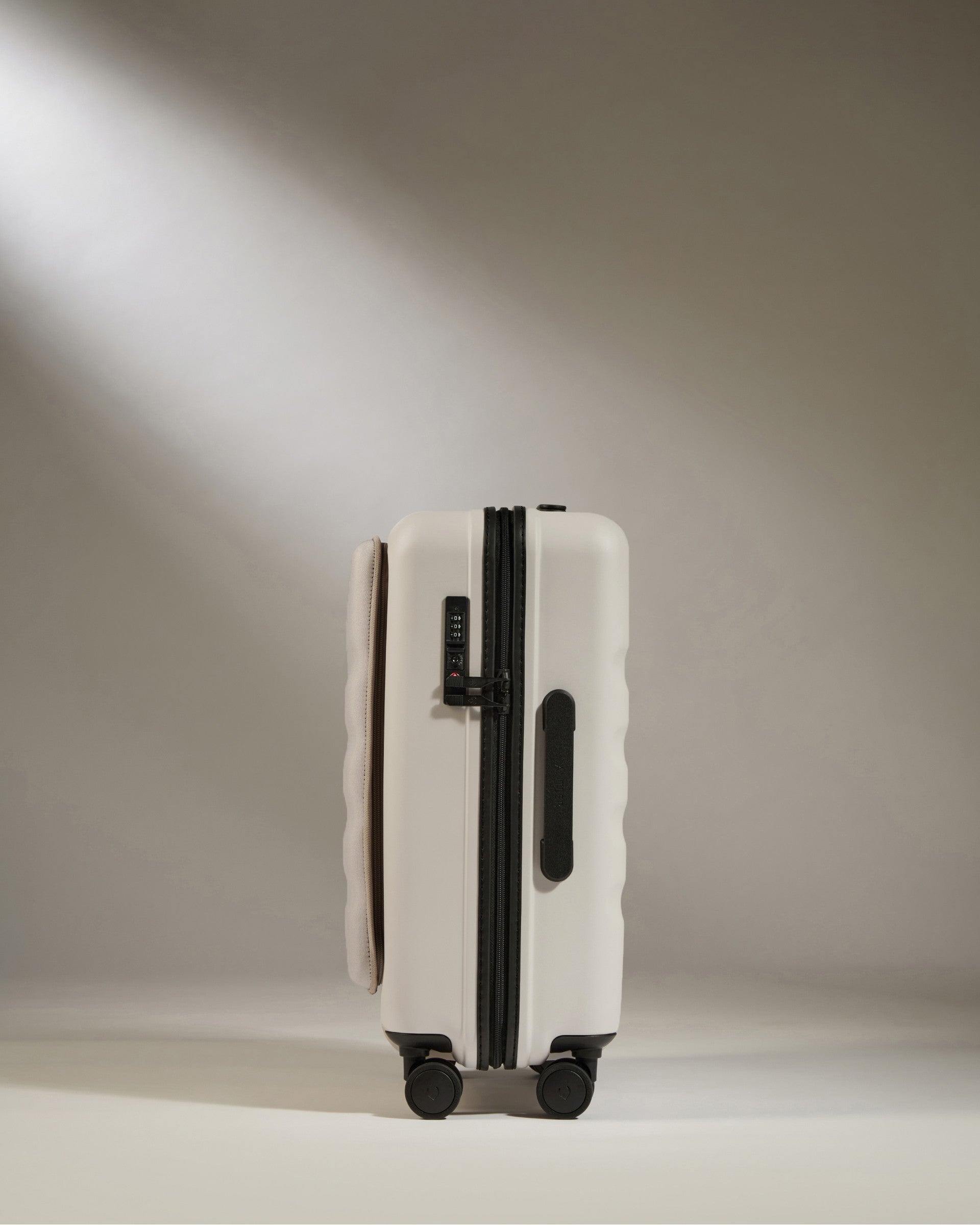 White suitcase with black handle and wheels on a neutral background