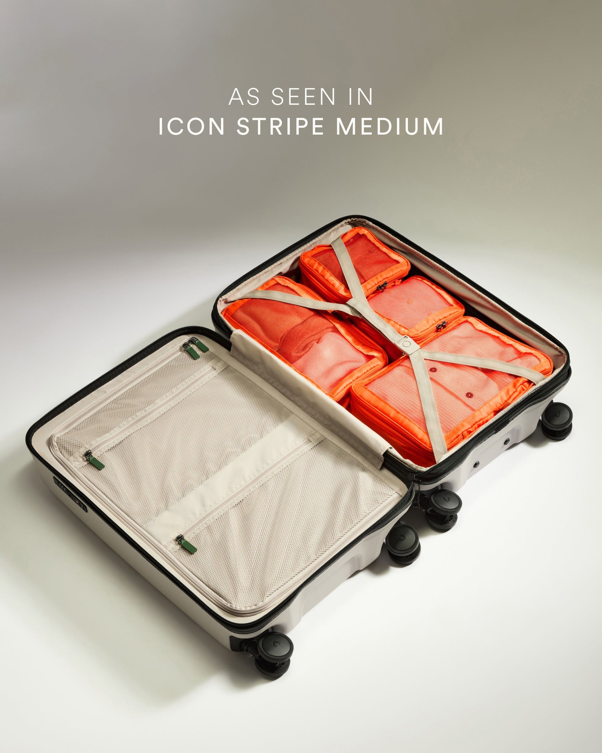 Open suitcase with orange packing cubes and text 'As seen in Icon Stripe Medium' on a light background