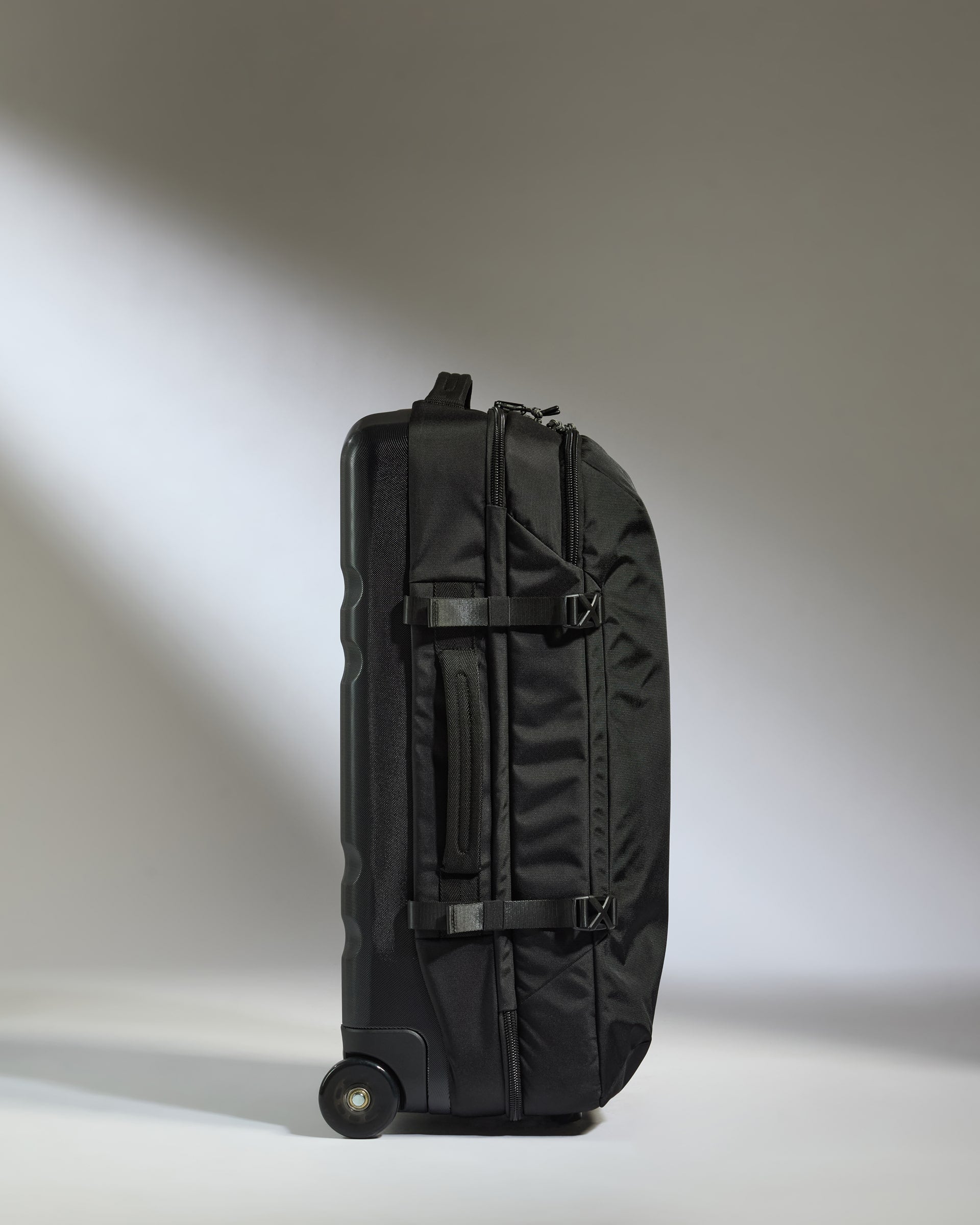 Black rolling suitcase on a light gray background