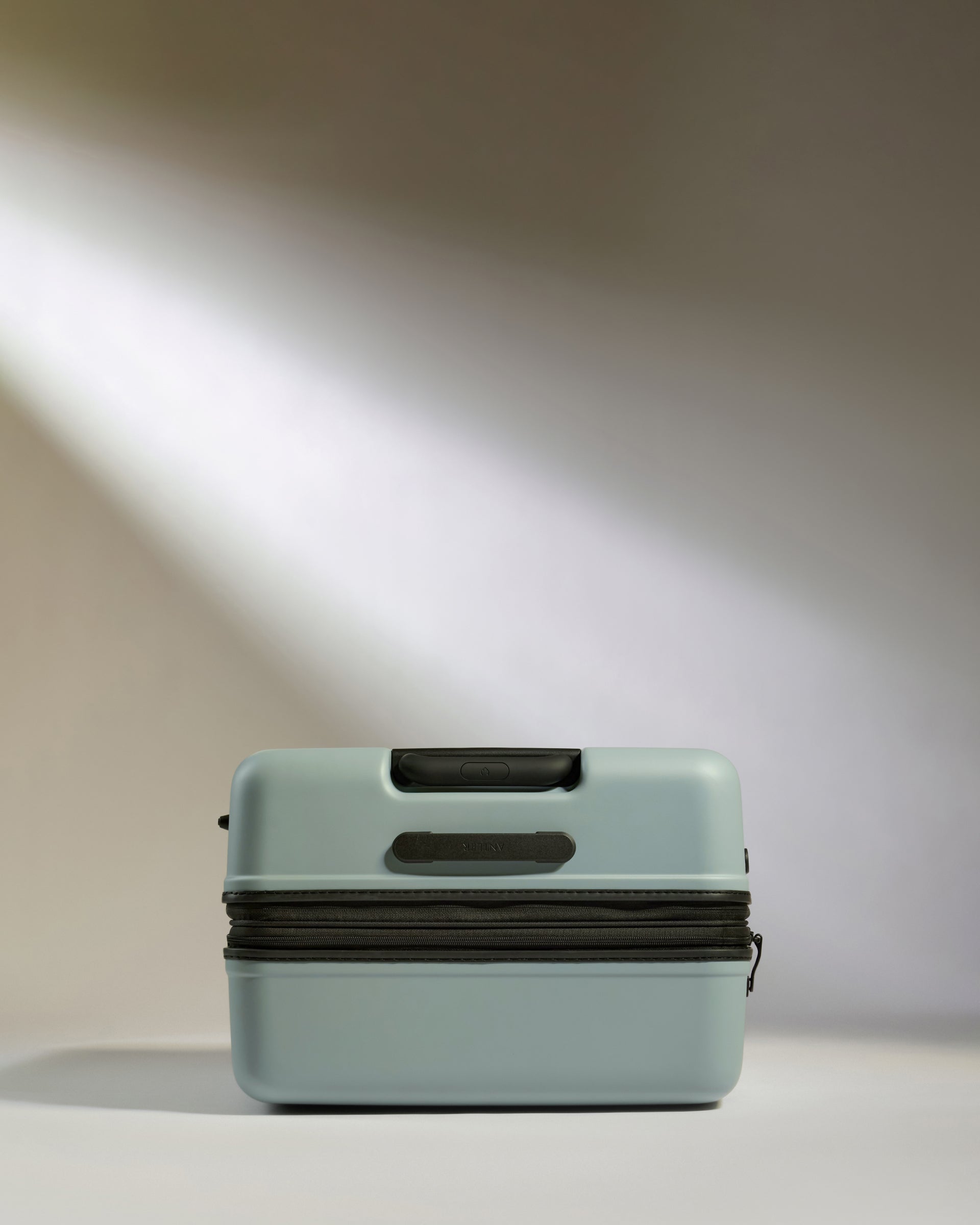 Light blue suitcase with black accents on a neutral background