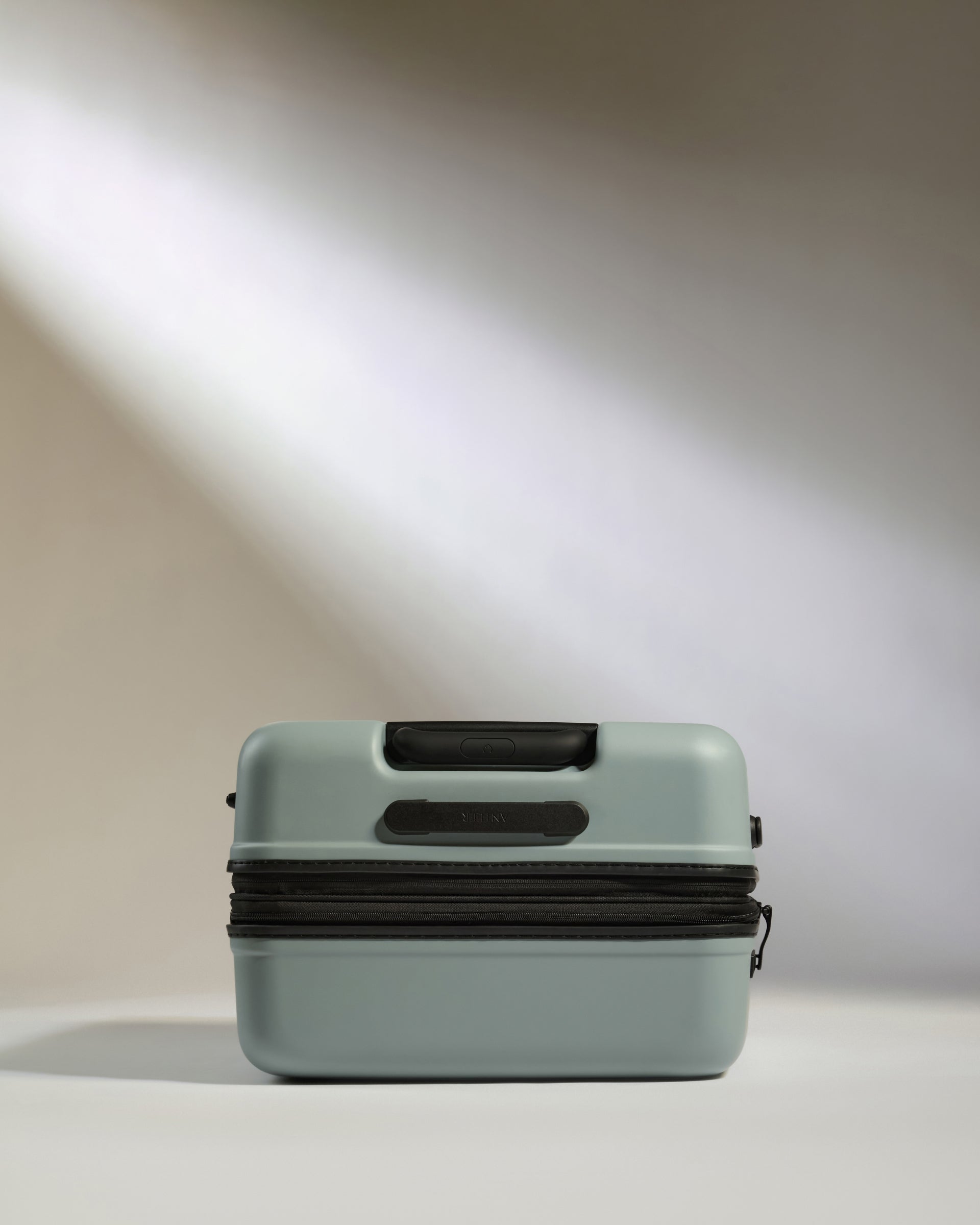 Light blue suitcase with black handle on a neutral background