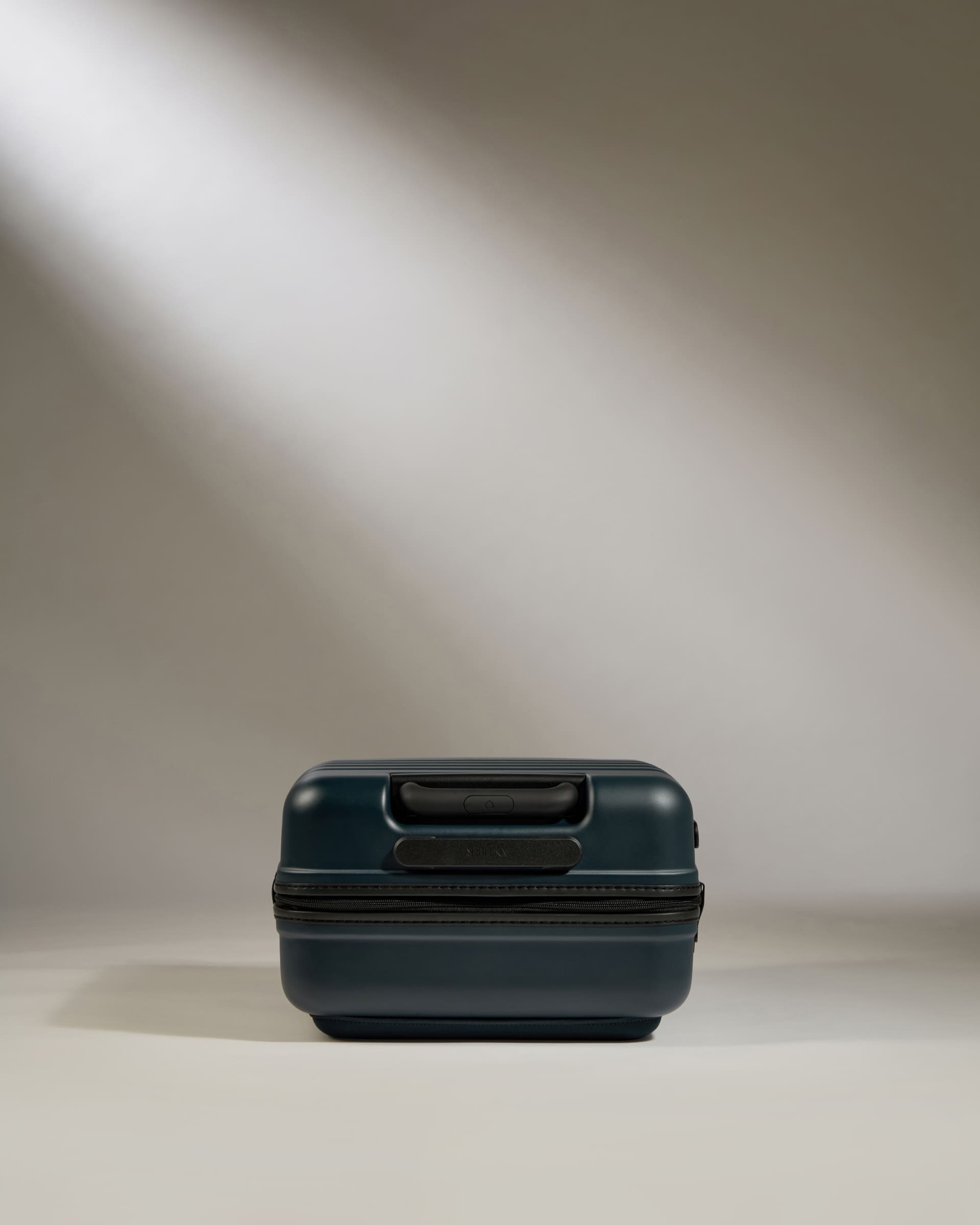 Dark green suitcase on a neutral background
