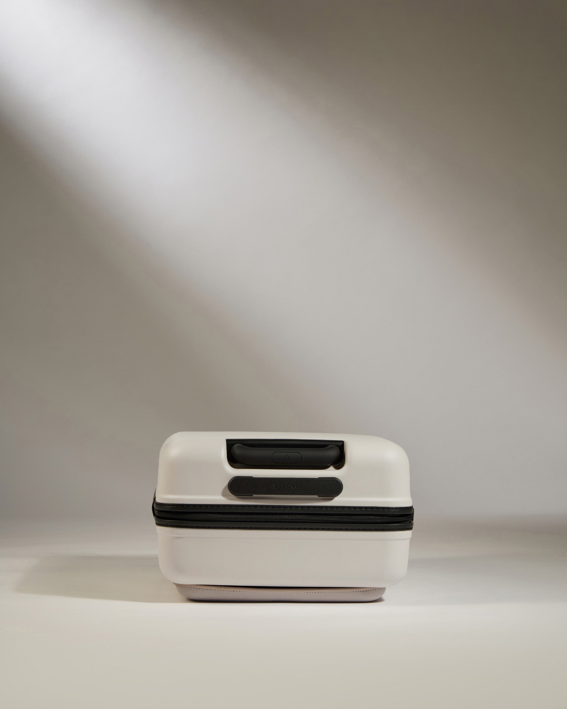 White suitcase with black accents on a neutral background