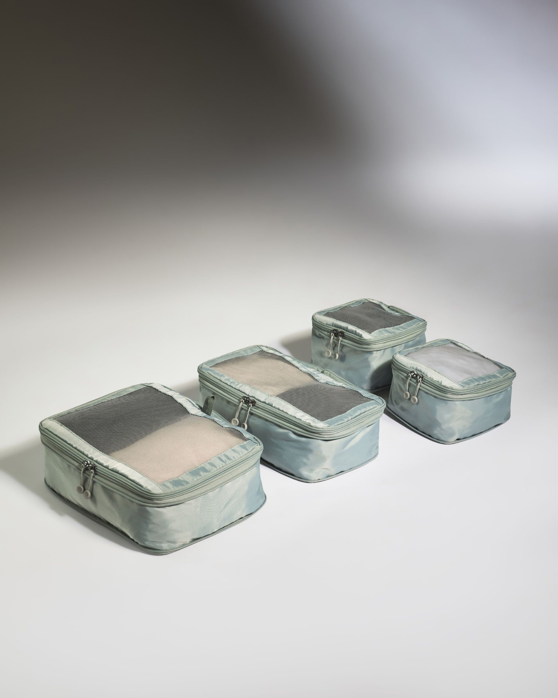 Set of five green travel packing cubes on a gray background