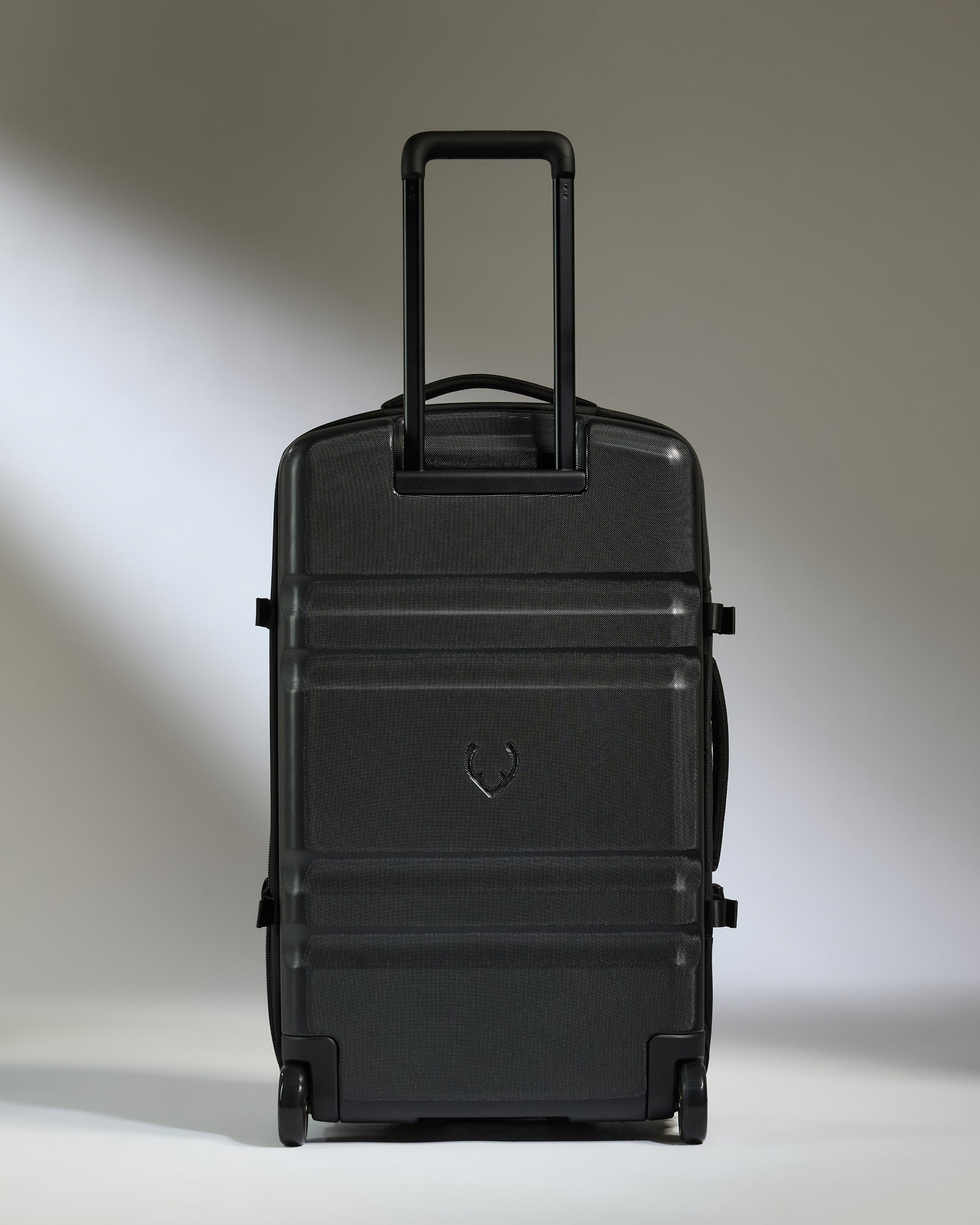 Black suitcase with a heart emblem on a neutral background