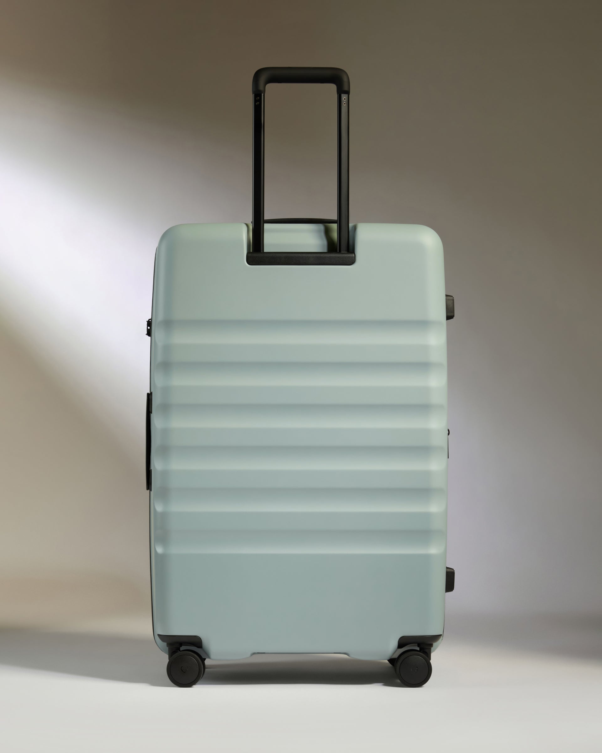 Light blue suitcase with a black handle on a gradient background