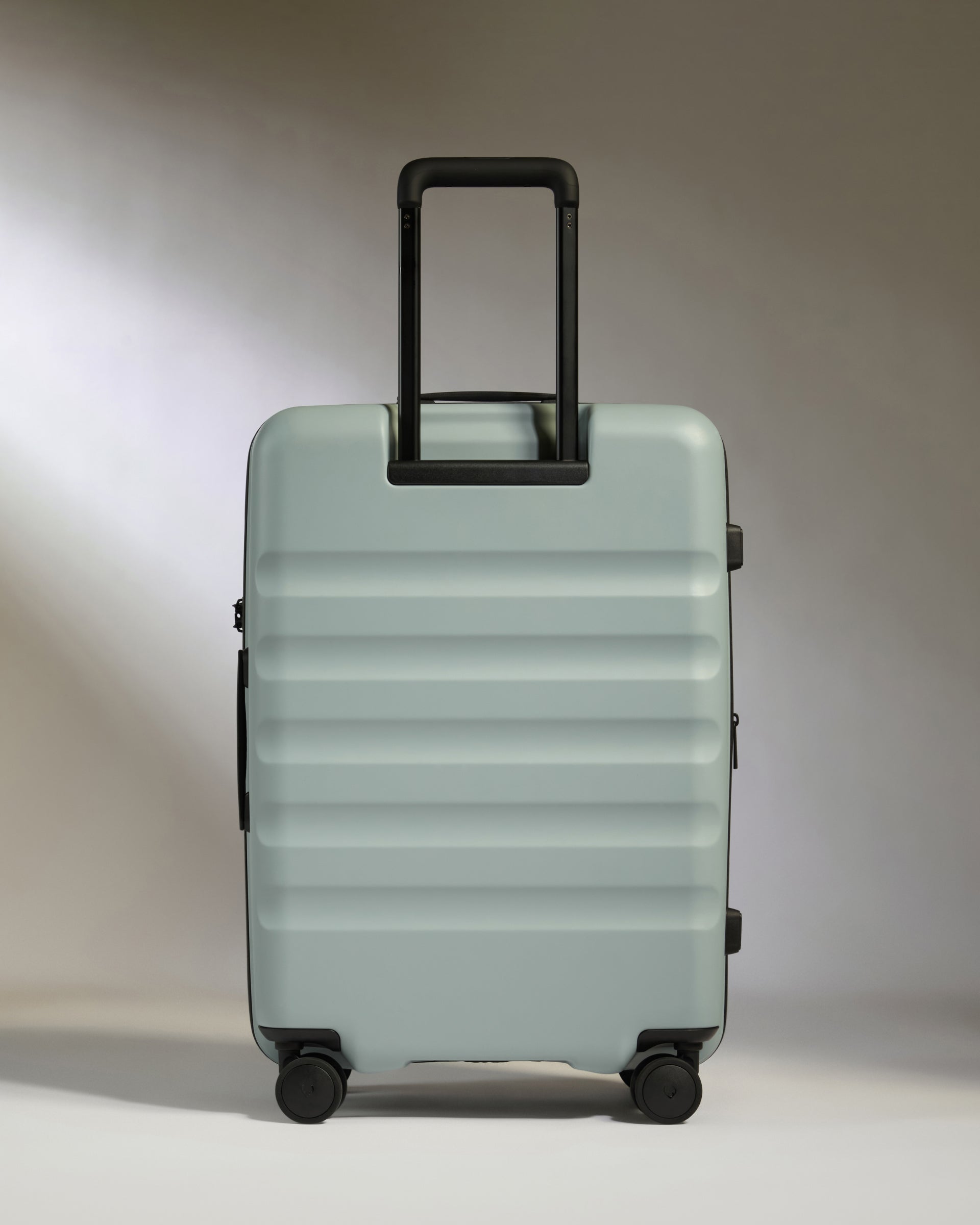 Light blue suitcase with black handle and wheels on a neutral background