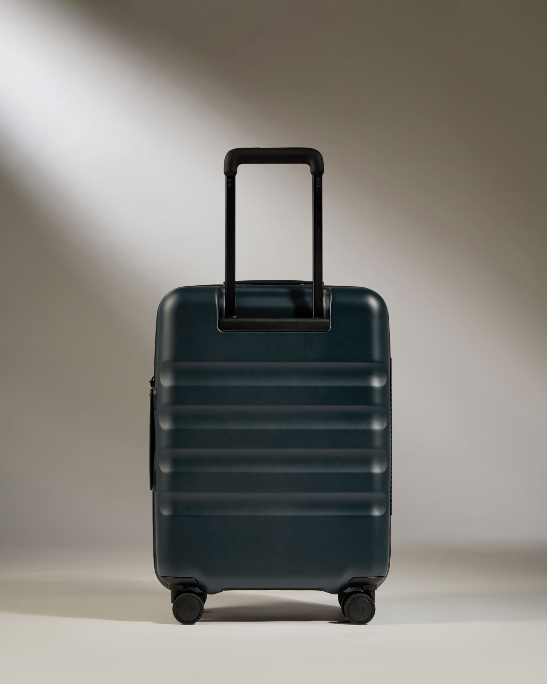 Dark green suitcase with a black handle on a neutral background