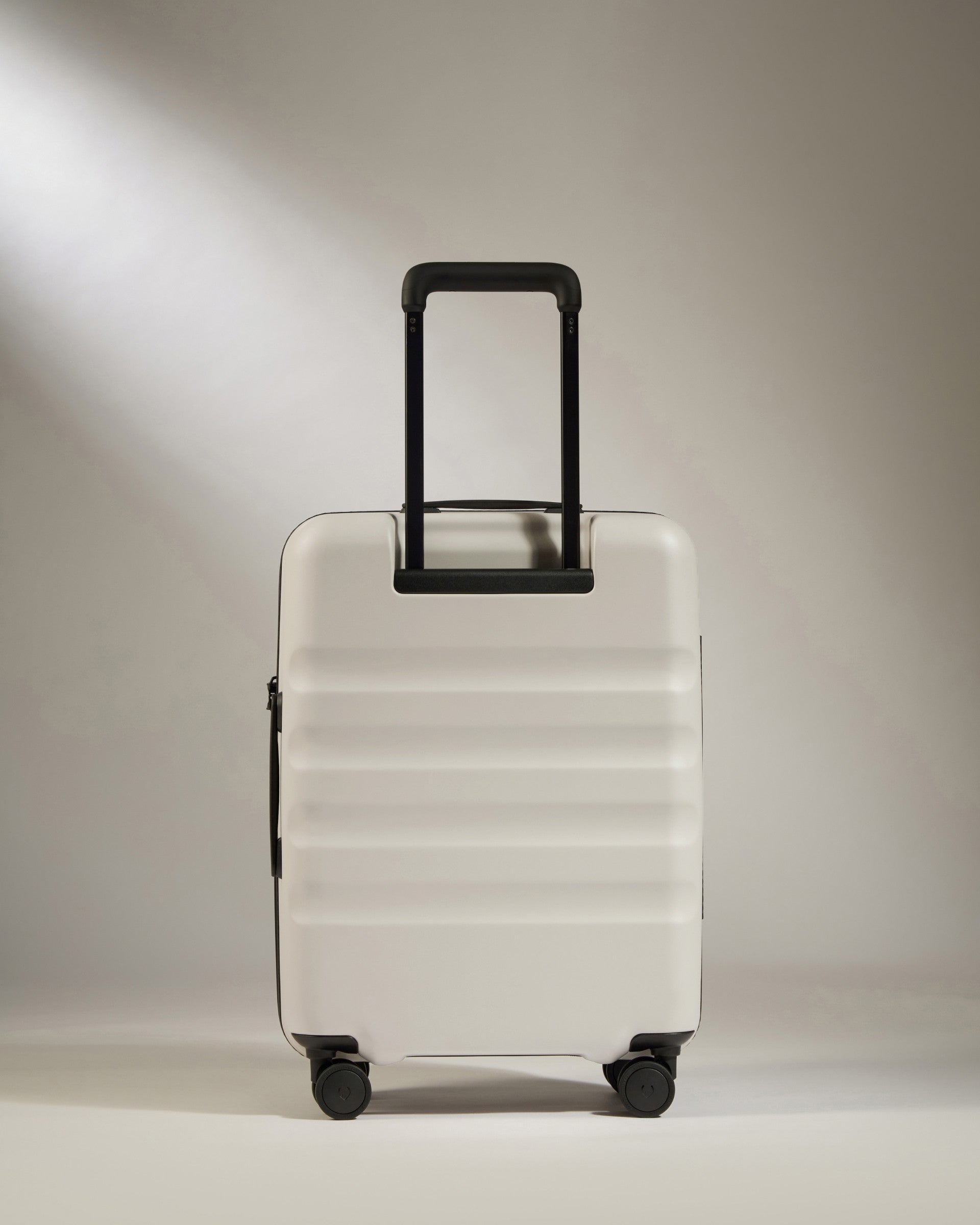 White suitcase with black handle on a light gray background