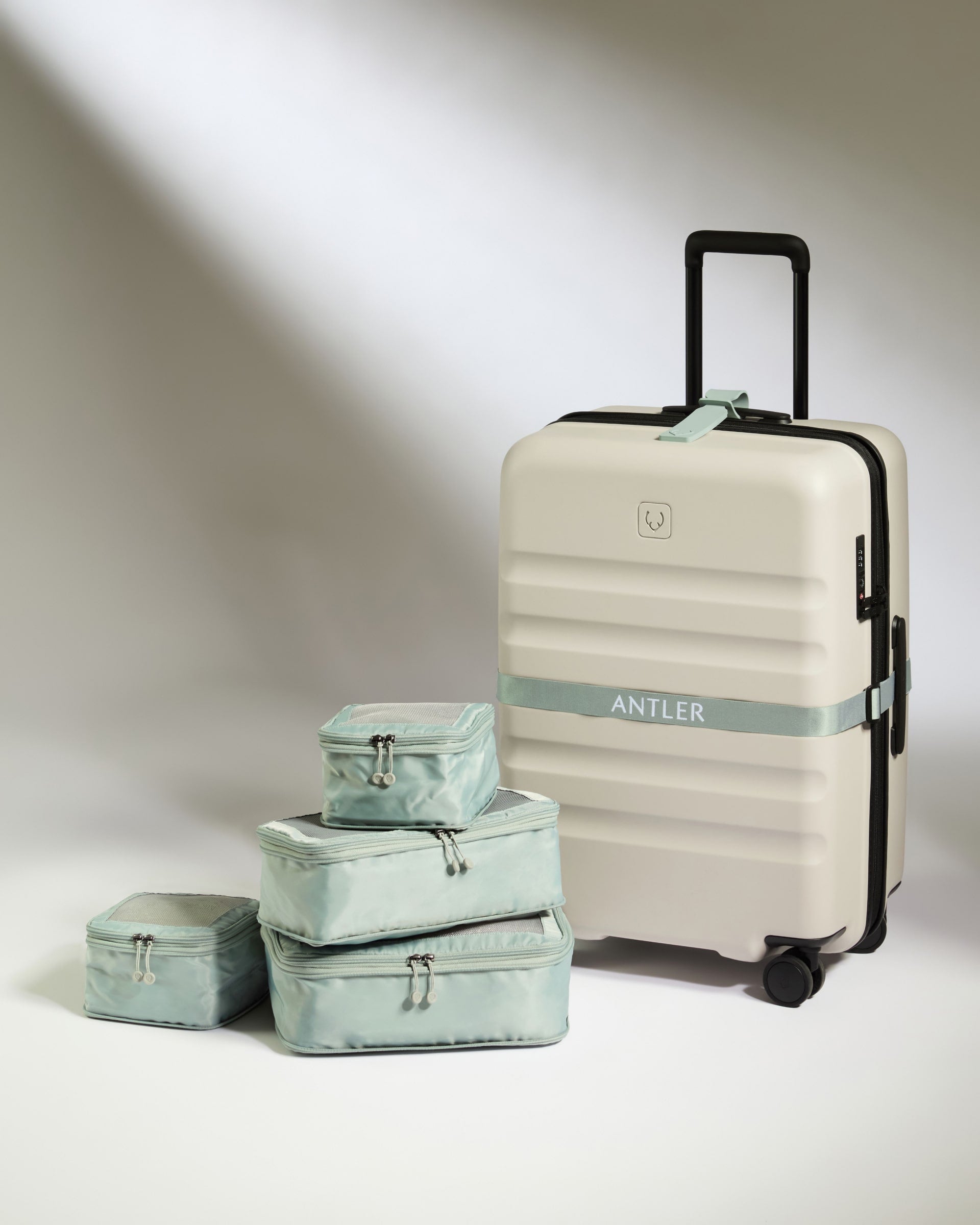 Beige suitcase with green packing cubes on a light background