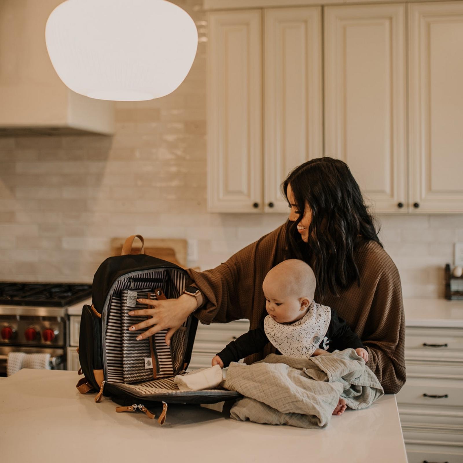 Woman and child in a kitchen with a backpack on a counter