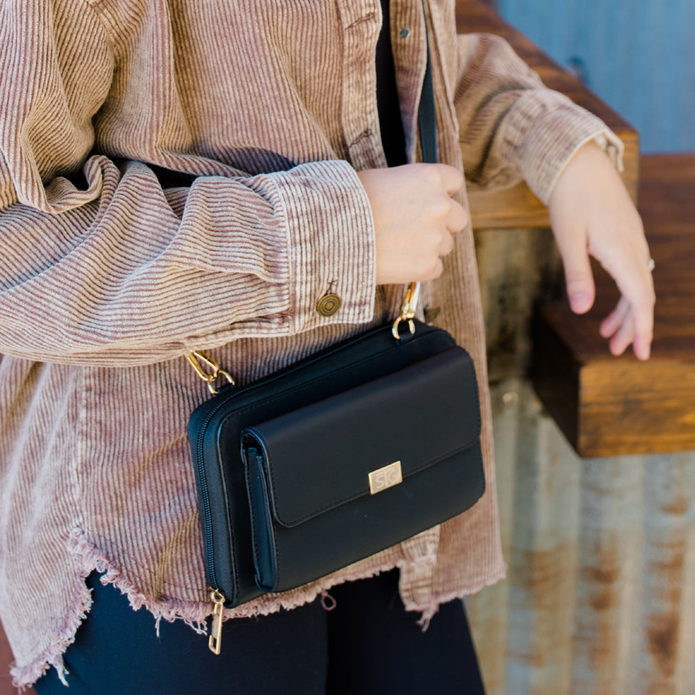 Person holding a black handbag with a blurred background