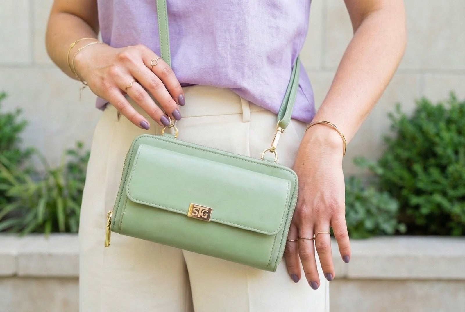 Person holding a green handbag with a blurred background