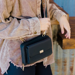 Person holding a black handbag with a blurred background