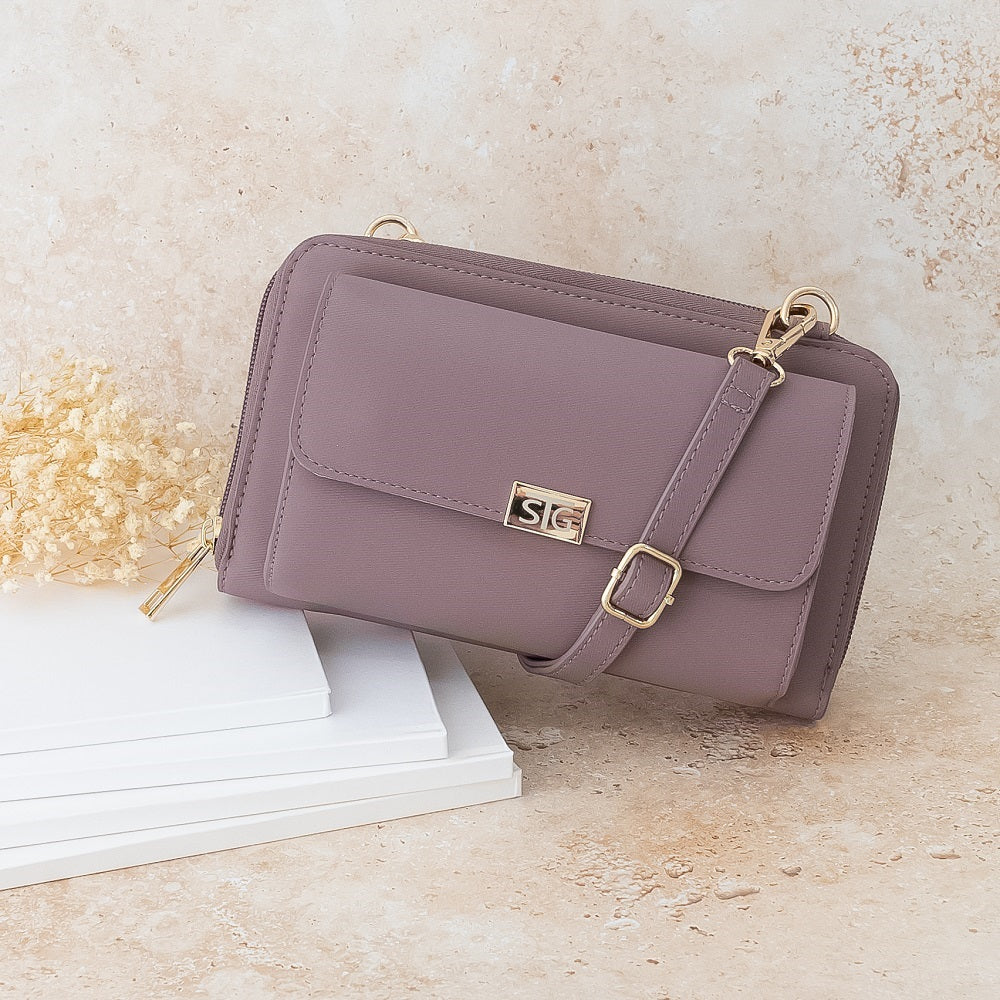 Purple handbag with gold accents on a light beige surface