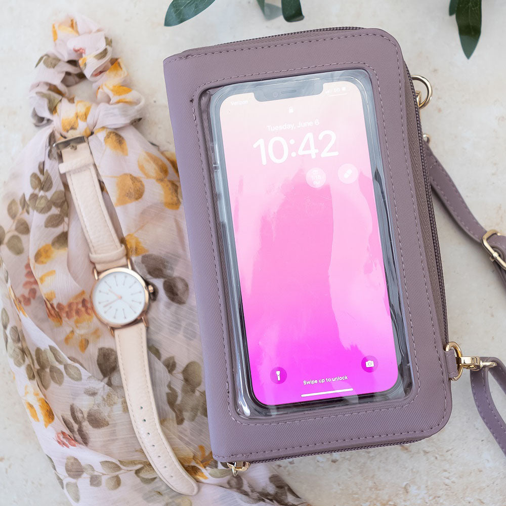 Purple phone case with a phone inside, next to a watch and floral scarf on a light background