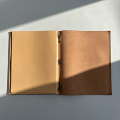 Open brown leather notebook on a light gray background