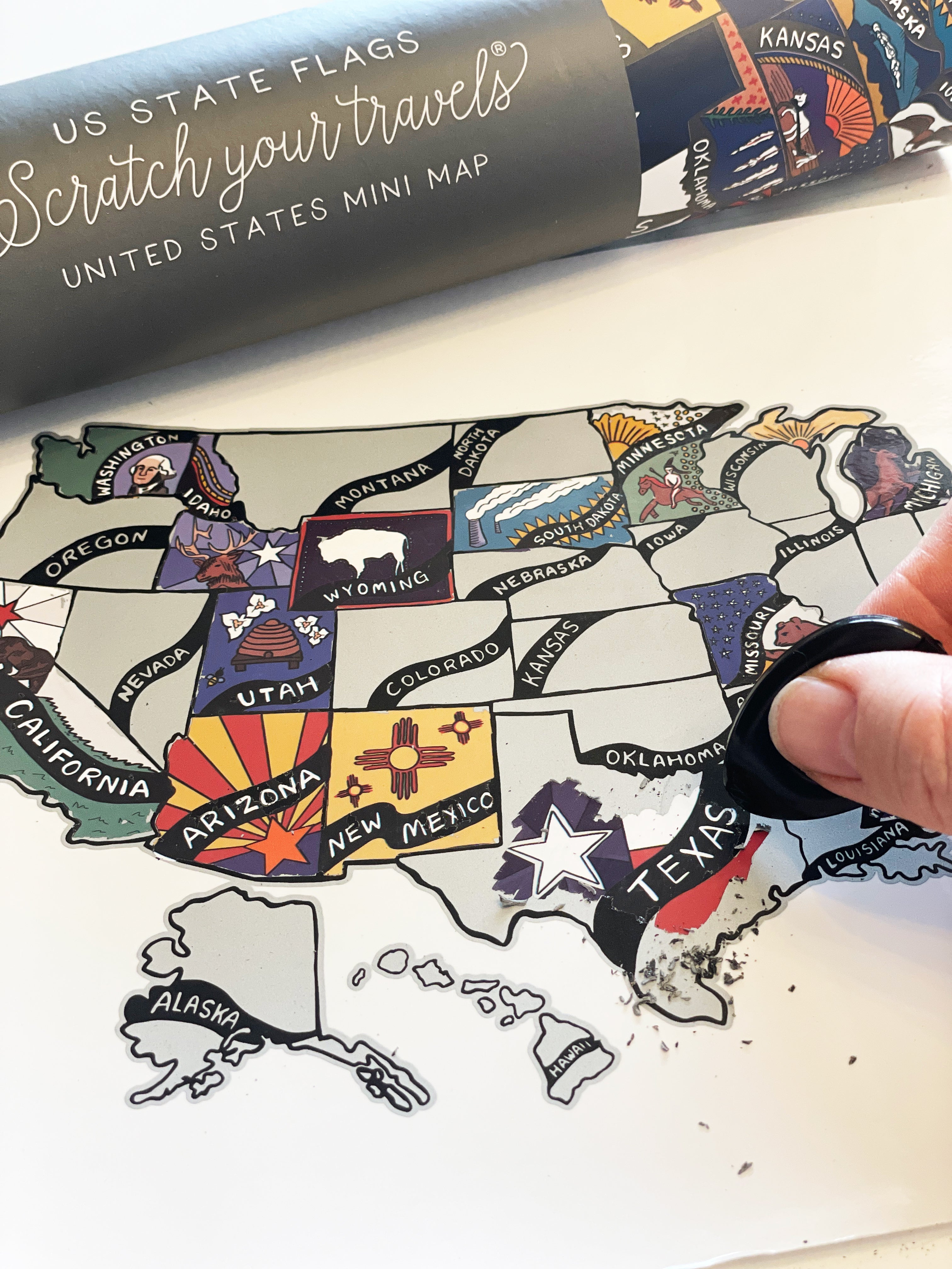 Map of the United States with state flags, being scratched off by a hand.