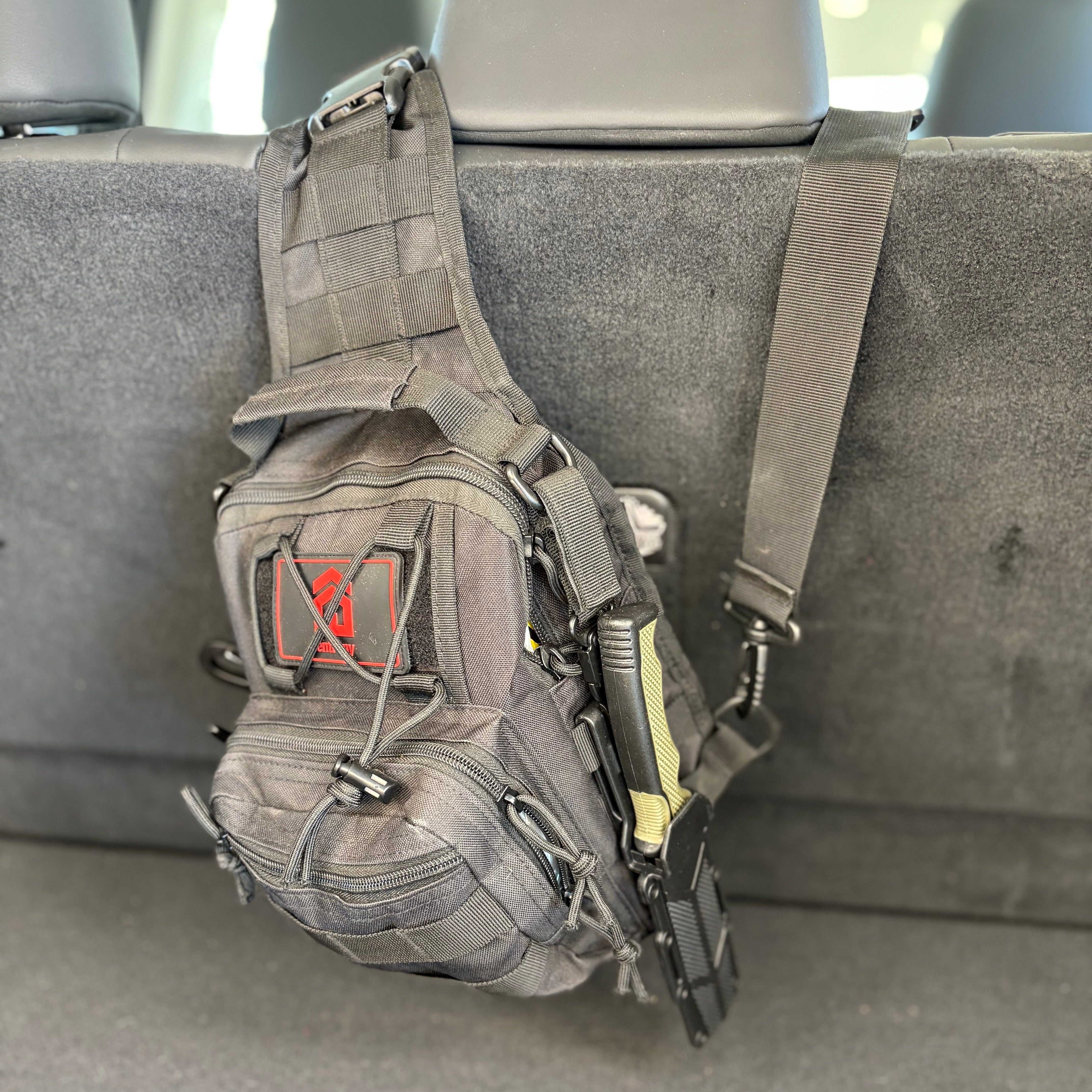 Gray tactical sling bag with visible brand logo on a car seat