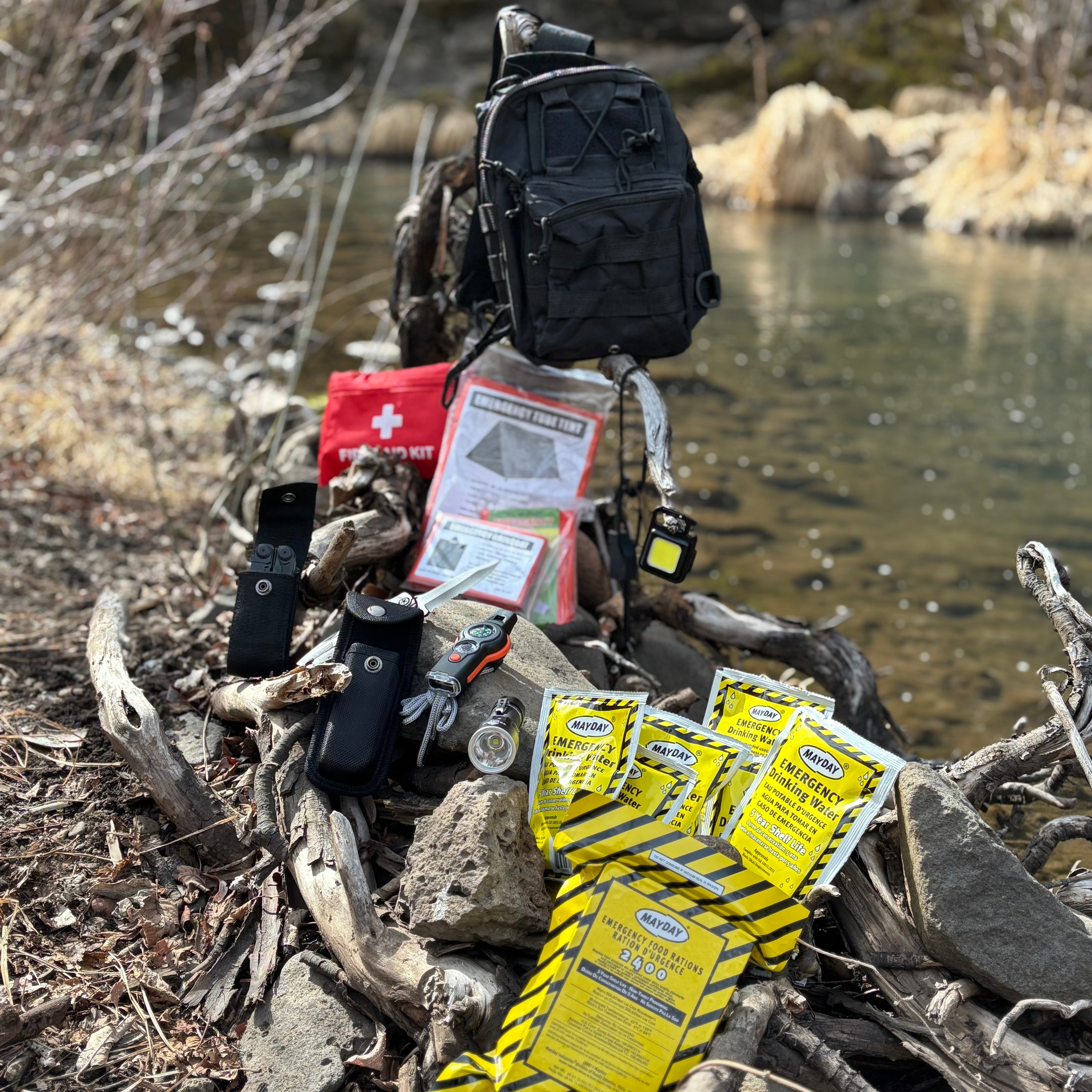Backpack with emergency supplies including a first aid kit and matches near a body of water.